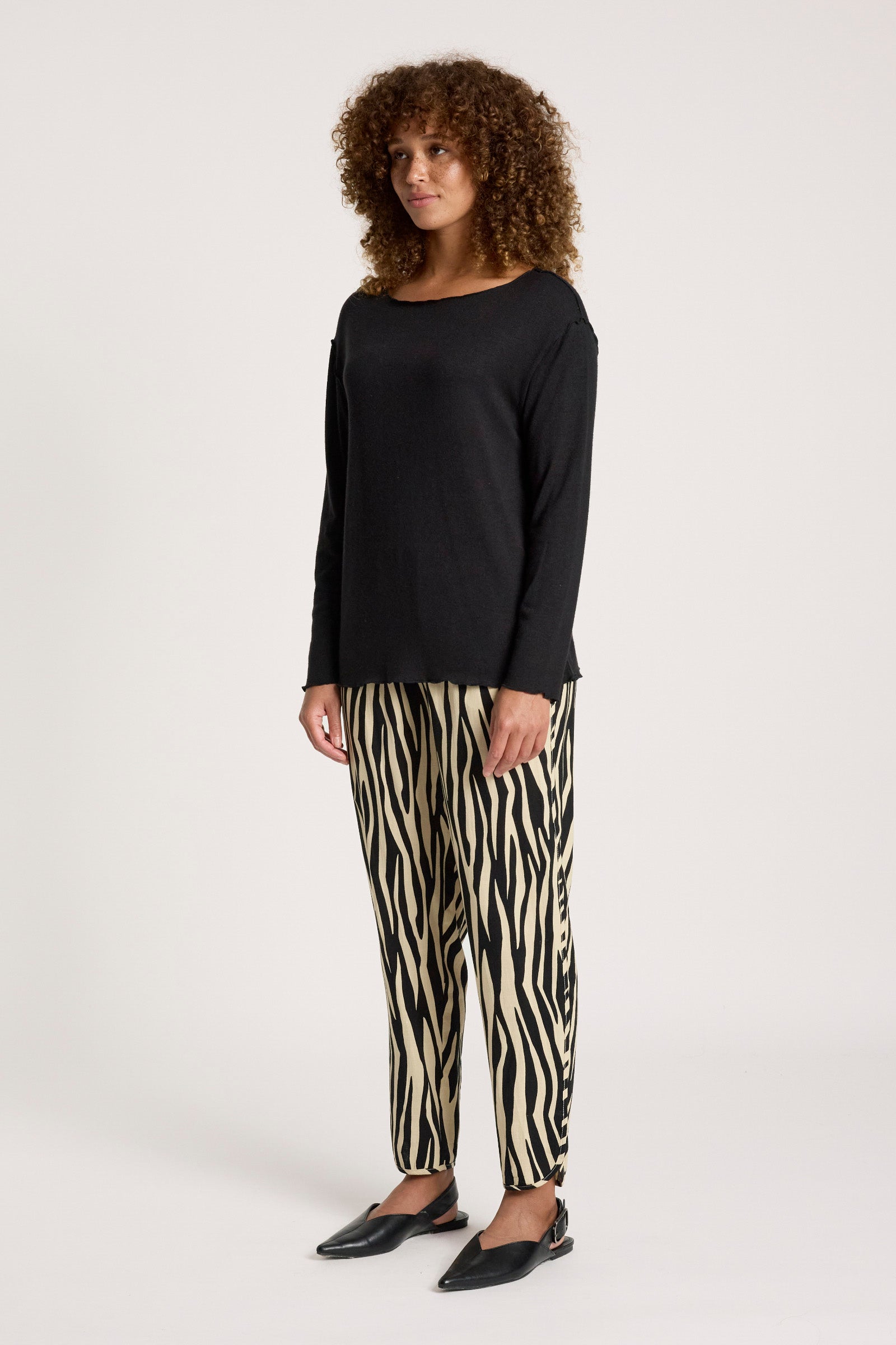 Image of Woman wearing a Eb & Ive black top and zebra print pants on a white background