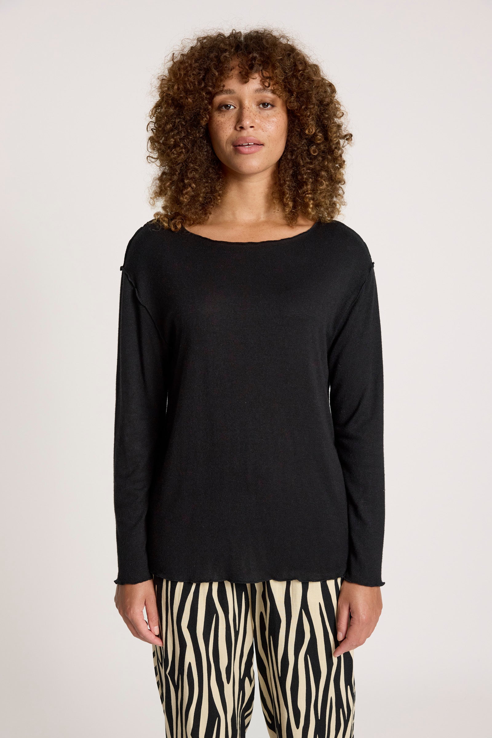 Image of Woman wearing a Eb & Ive black long-sleeve top and zebra print pants on a plain background