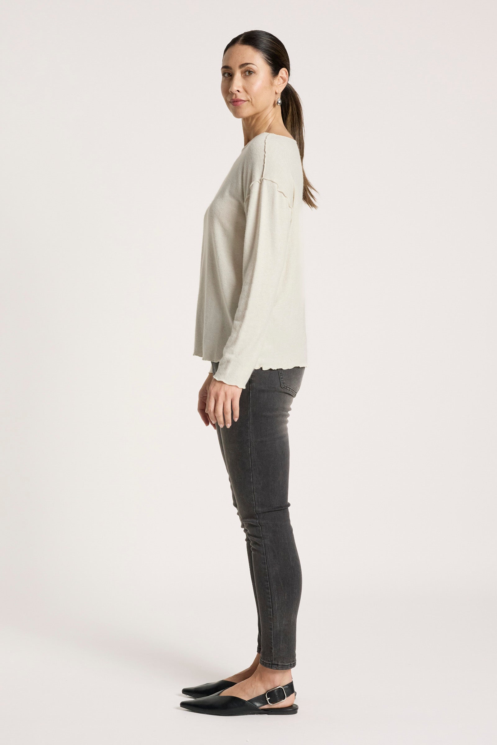 Woman wearing a Eb & Ive light-colored top and dark jeans on a white background