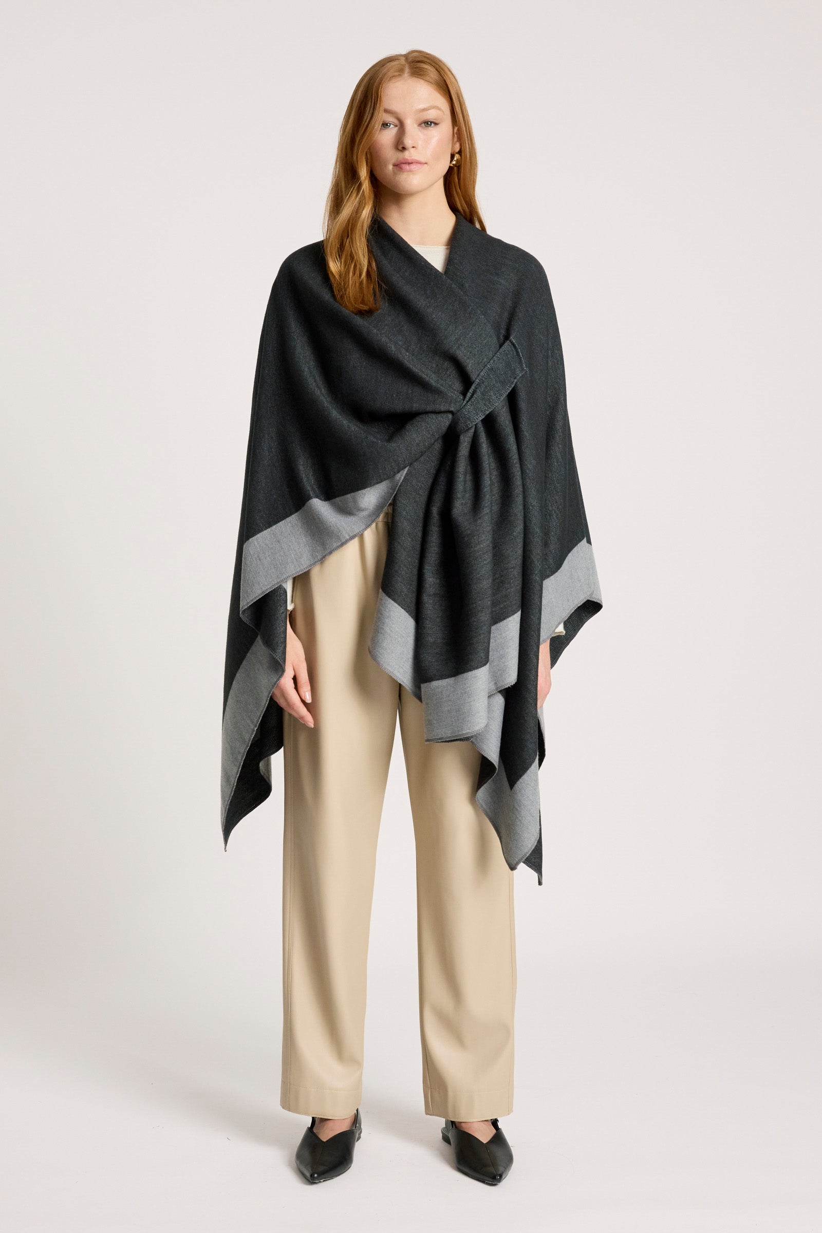 Image of Woman wearing a Eb & Ive black and gray patterned poncho over a beige outfit on a white background