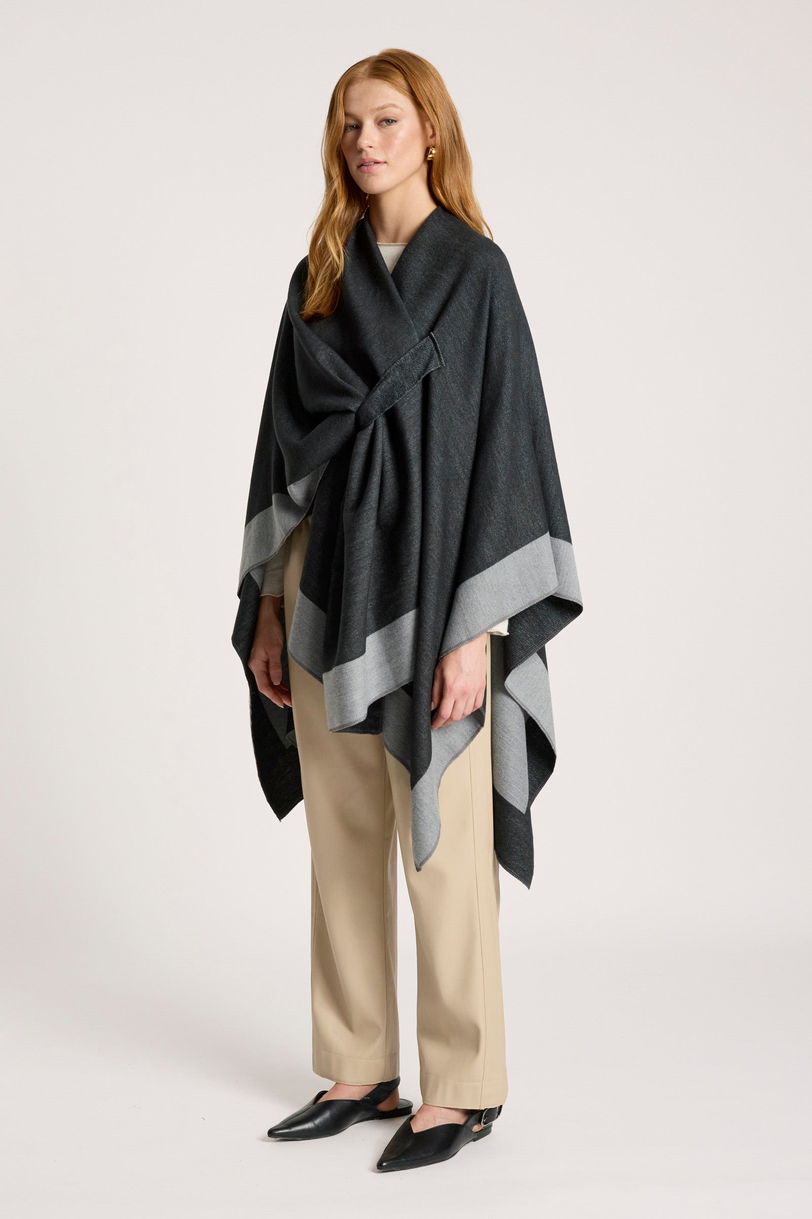 Woman wearing a Eb & Ive dark gray poncho with a patterned edge on a white background