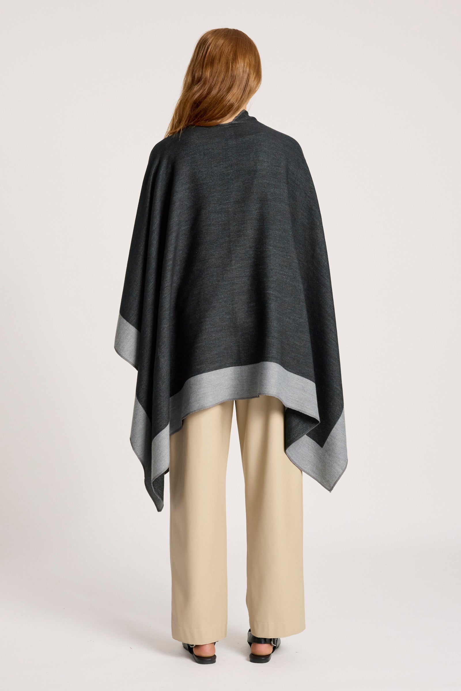 Person wearing a Eb & Ive dark gray poncho over a light-colored outfit on a white background