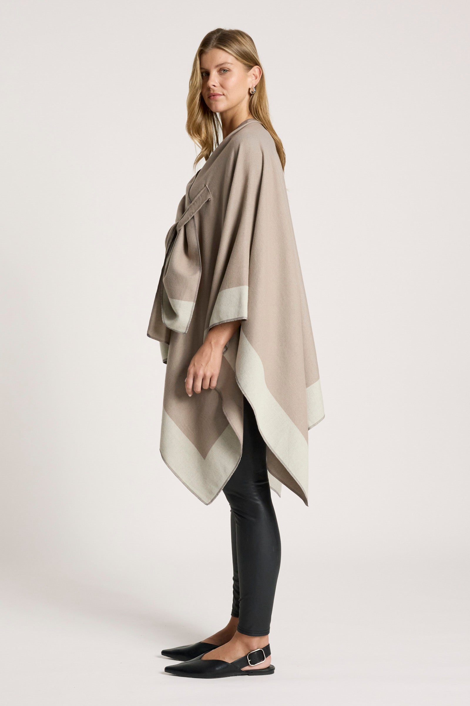 Image of Woman wearing a Eb and Ive beige and gray striped poncho on a white background