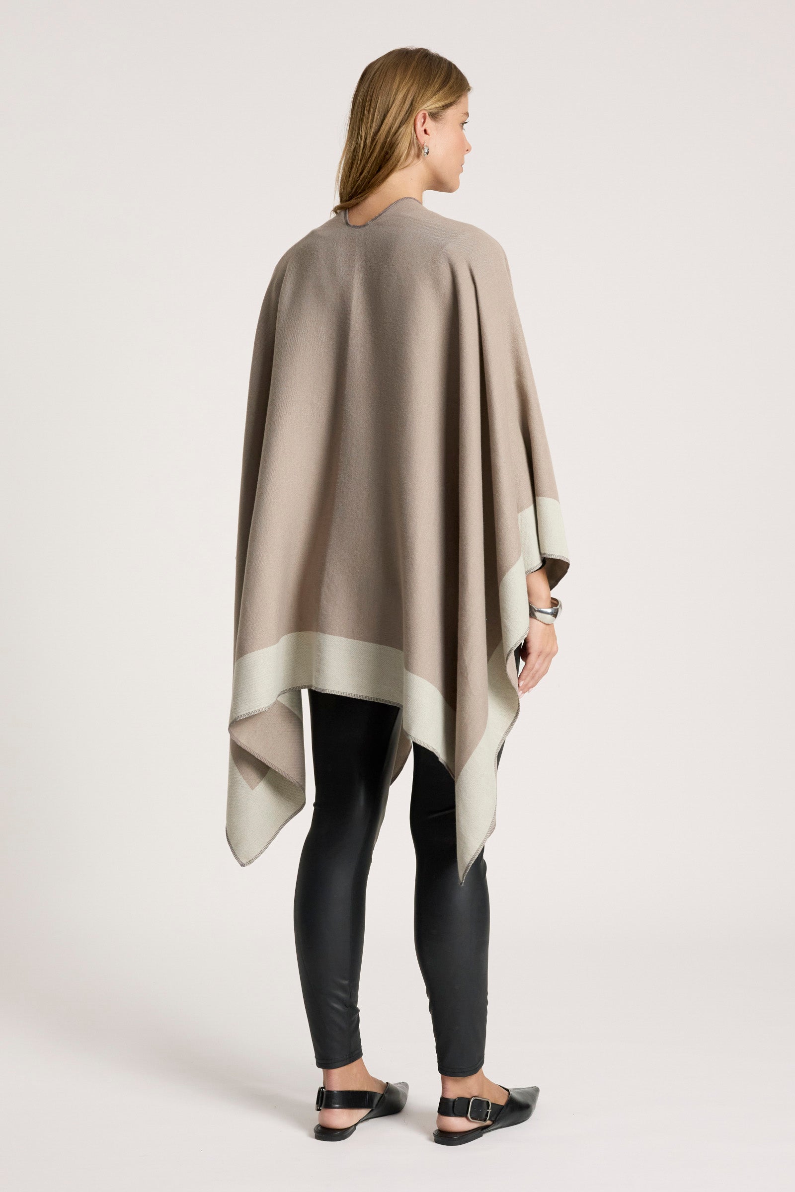 Image of Woman wearing a Eb & Ive beige poncho over a black outfit on a white background