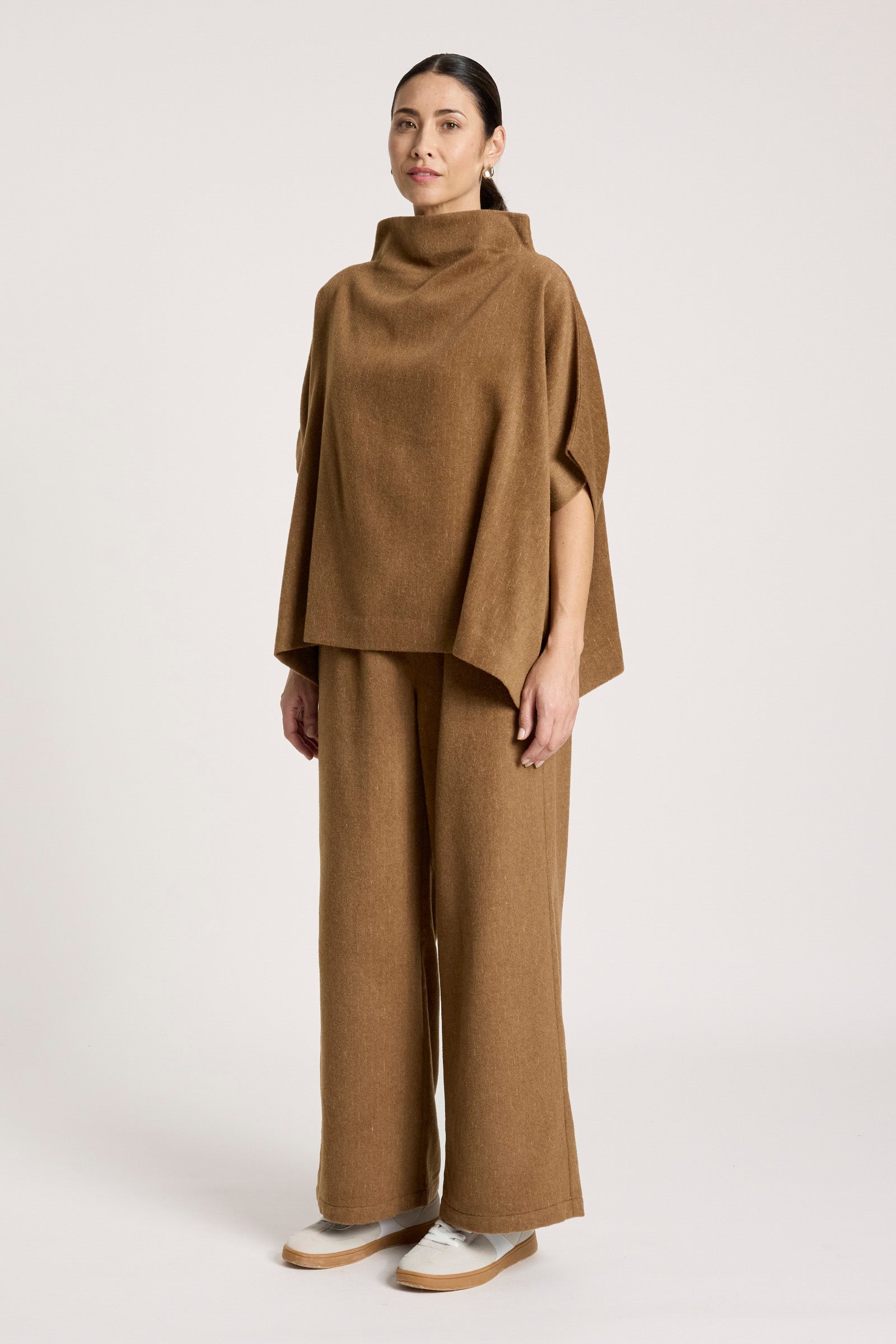 Image of Woman wearing a Eb & Ive brown poncho and wide-leg pants on a white background