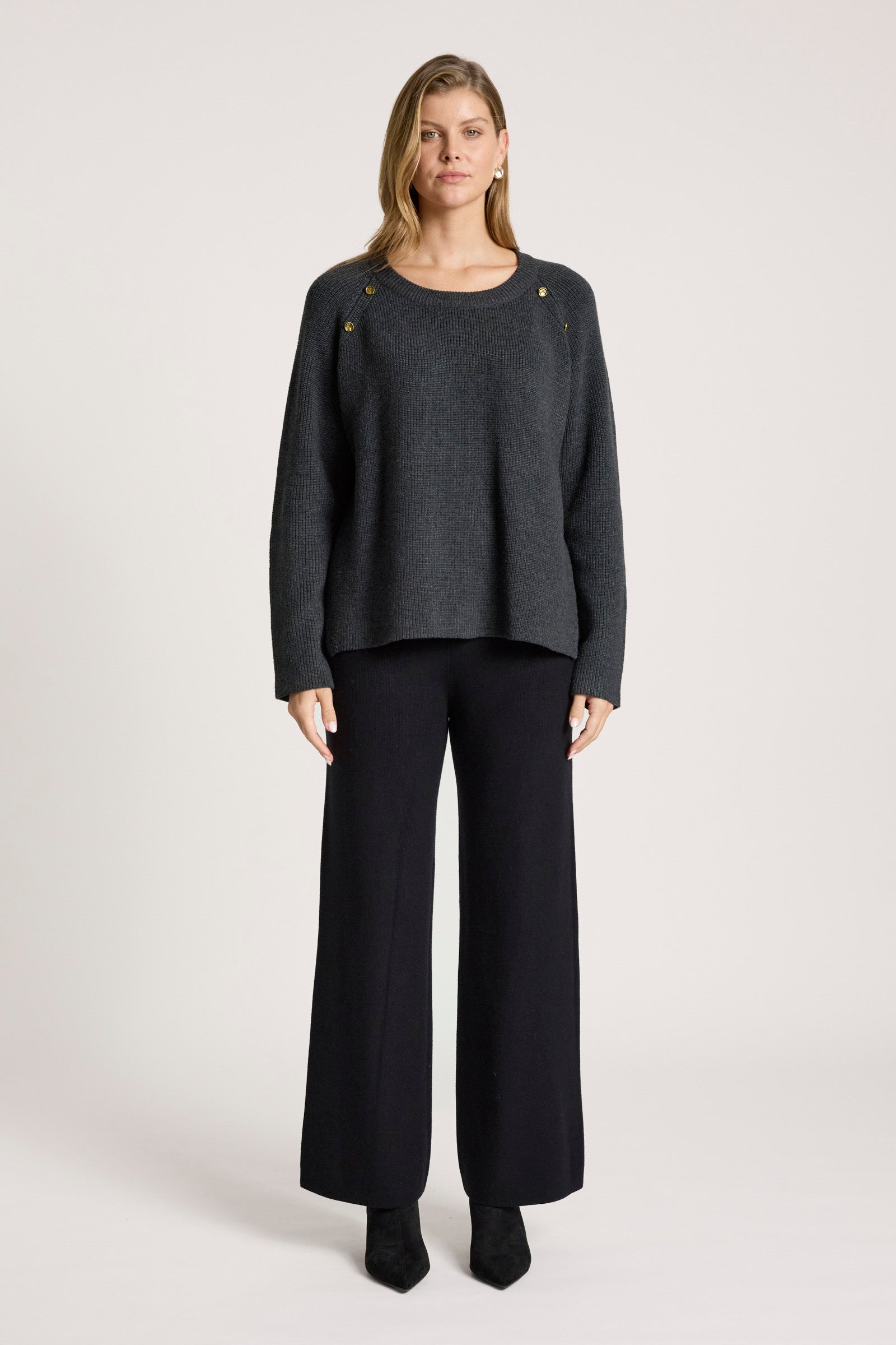 Woman wearing a Eb & Ive dark grey sweater and black pants on a white background