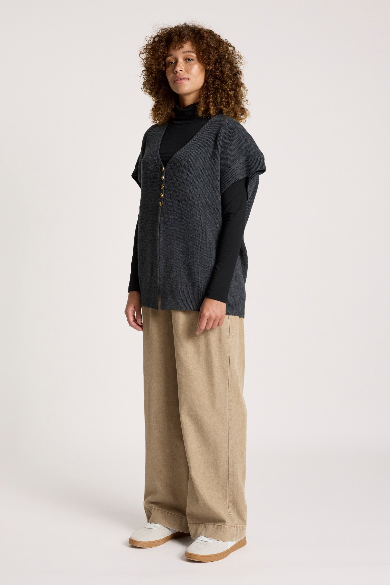 Image of Woman wearing a Eb & Ive dark grey cardigan over a black turtleneck with beige wide-leg pants on a white background