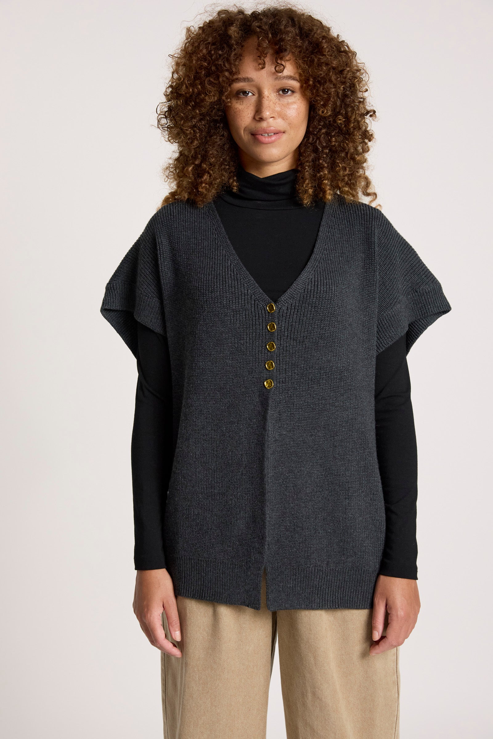 Image of Woman wearing a Eb & Ive dark grey cardigan over a black top with beige pants on a white background
