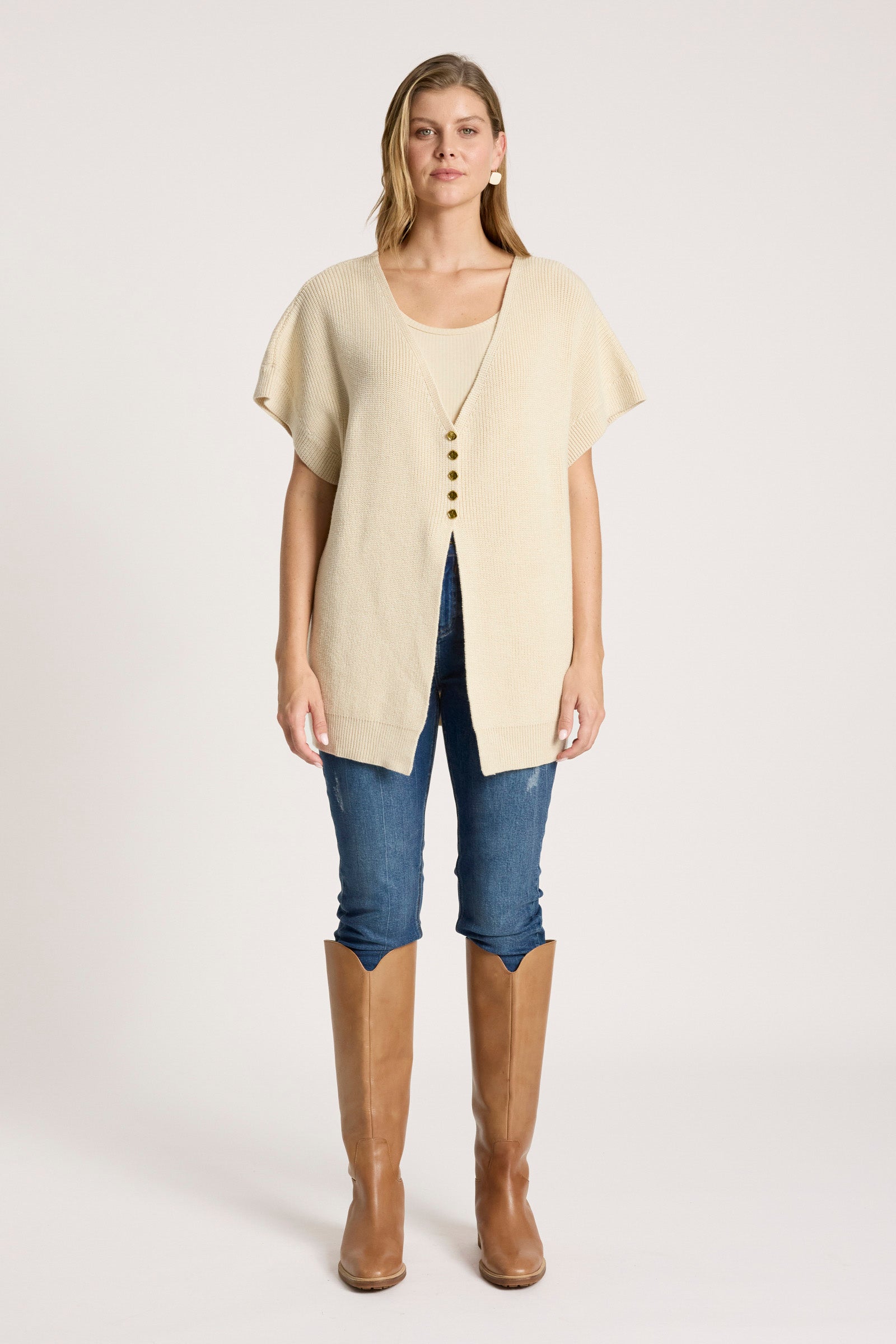 Image of Woman wearing a Eb & Ive beige cardigan, blue jeans, and brown knee-high boots on a white background