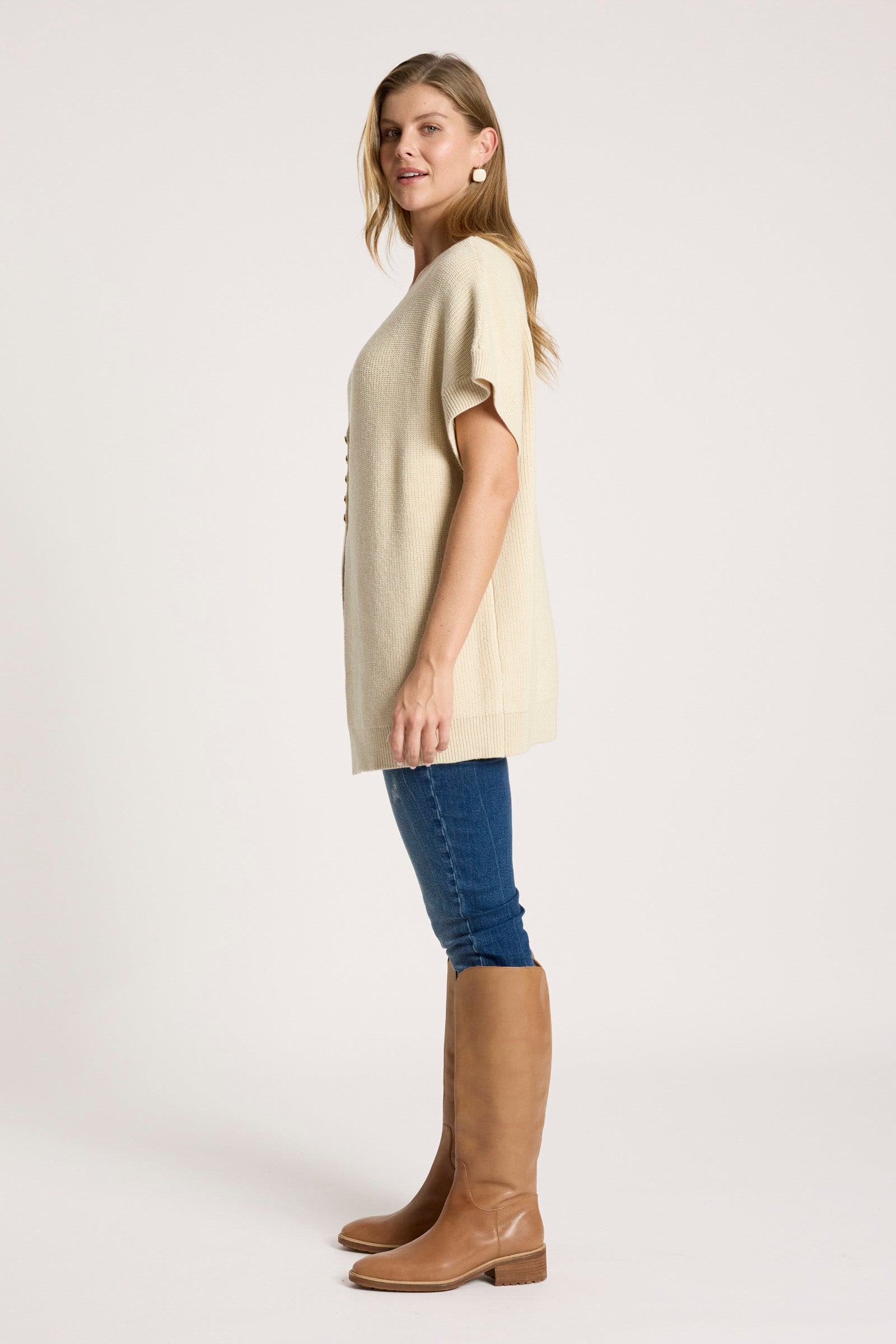 Image of Woman wearing a Eb & Ive beige sweater, blue jeans, and brown knee-high boots on a white background