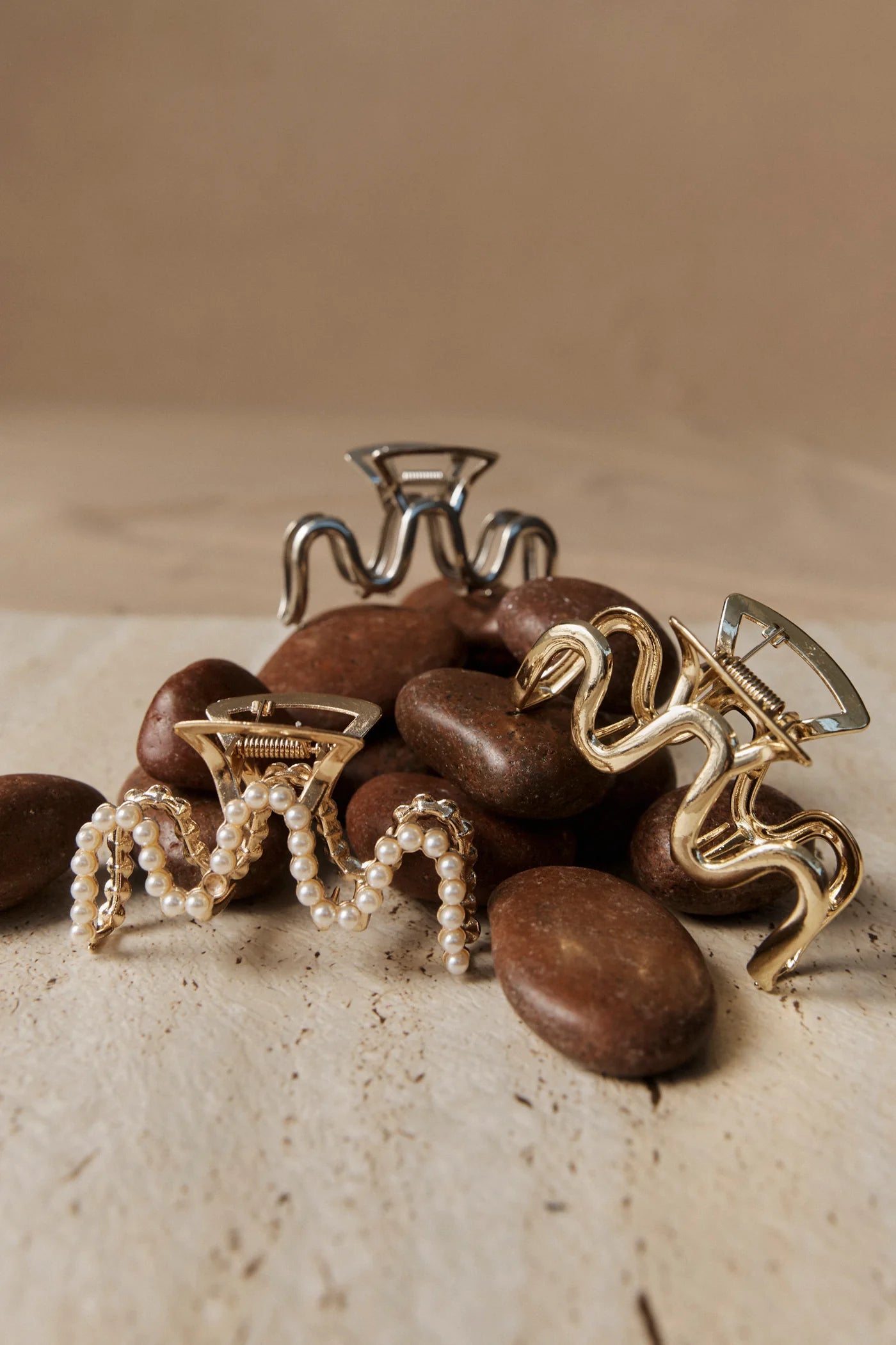 Image of Eb & Ive Gold and silver hair clips on a pile of brown stones with a beige background