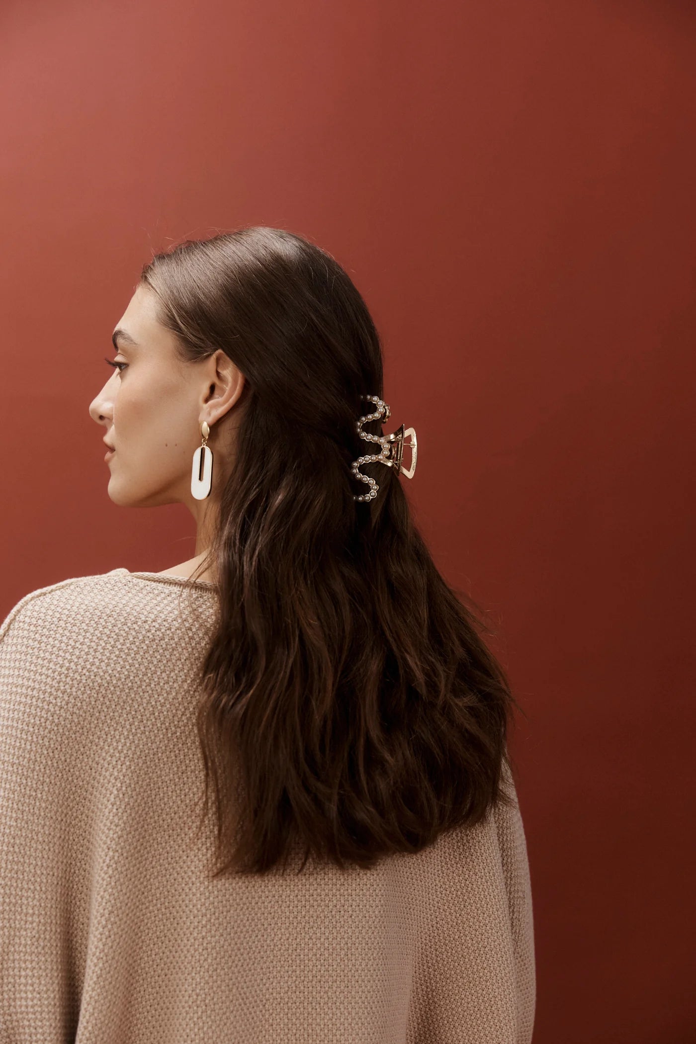 Woman wearing pearl eb and ive hair claw clip on a orange background