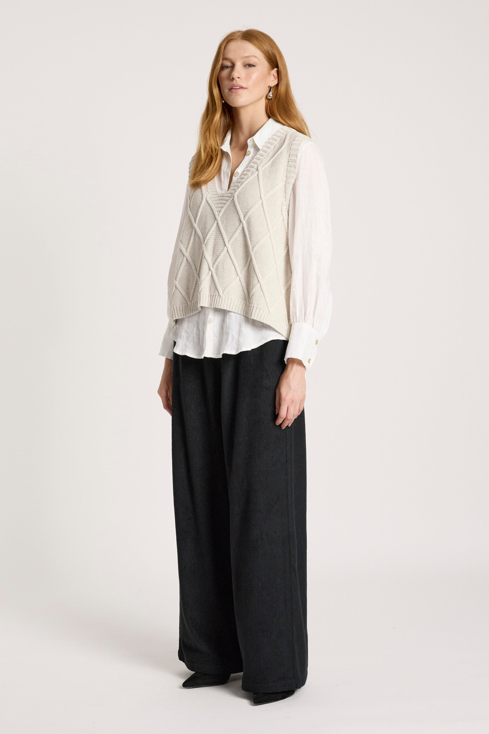 Image of Woman wearing a Eb and Ive white shirt, cream vest, and black pants on a white background