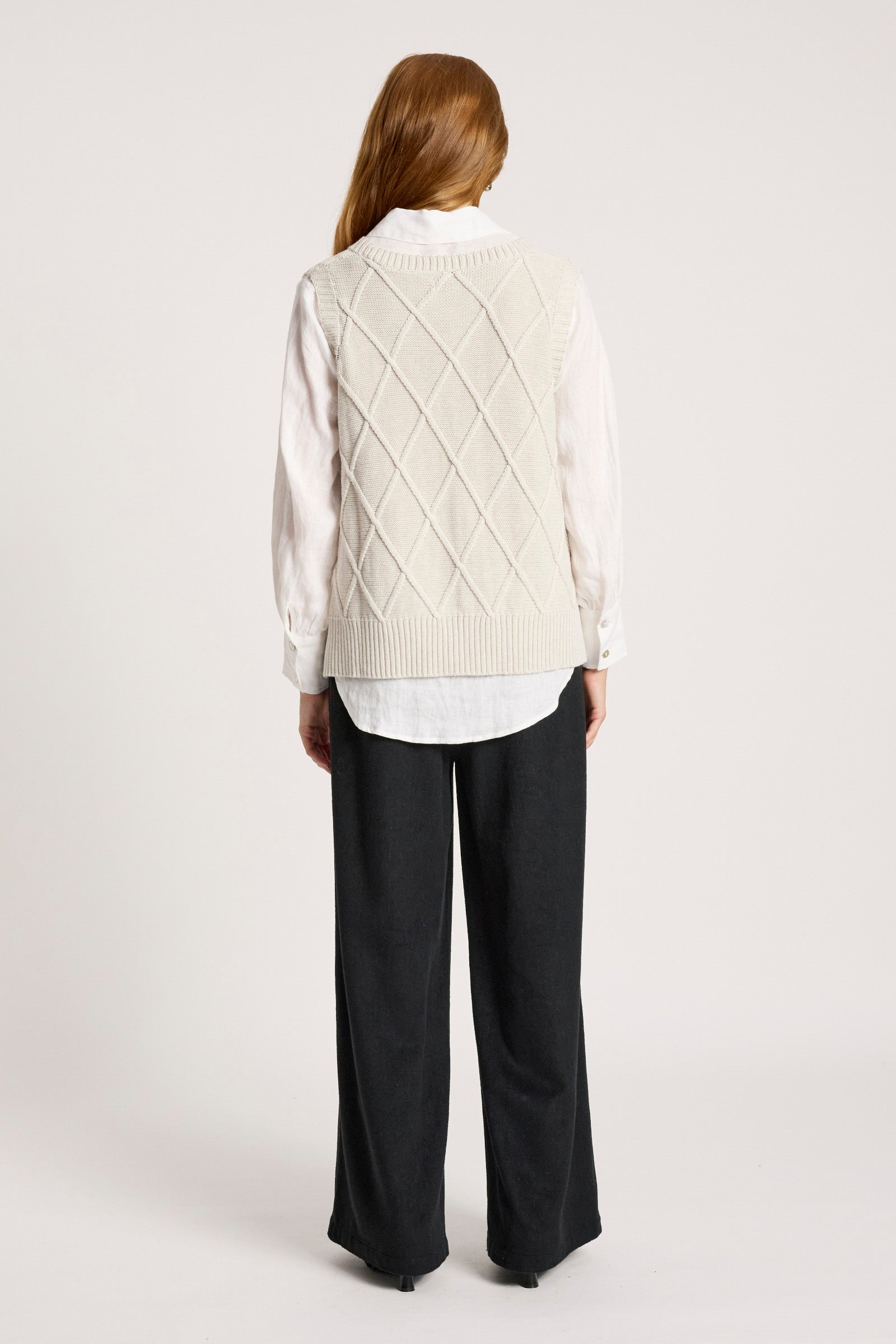 Image of Person wearing a Eb and Ive cream knitted vest over a white shirt and black pants on a white background