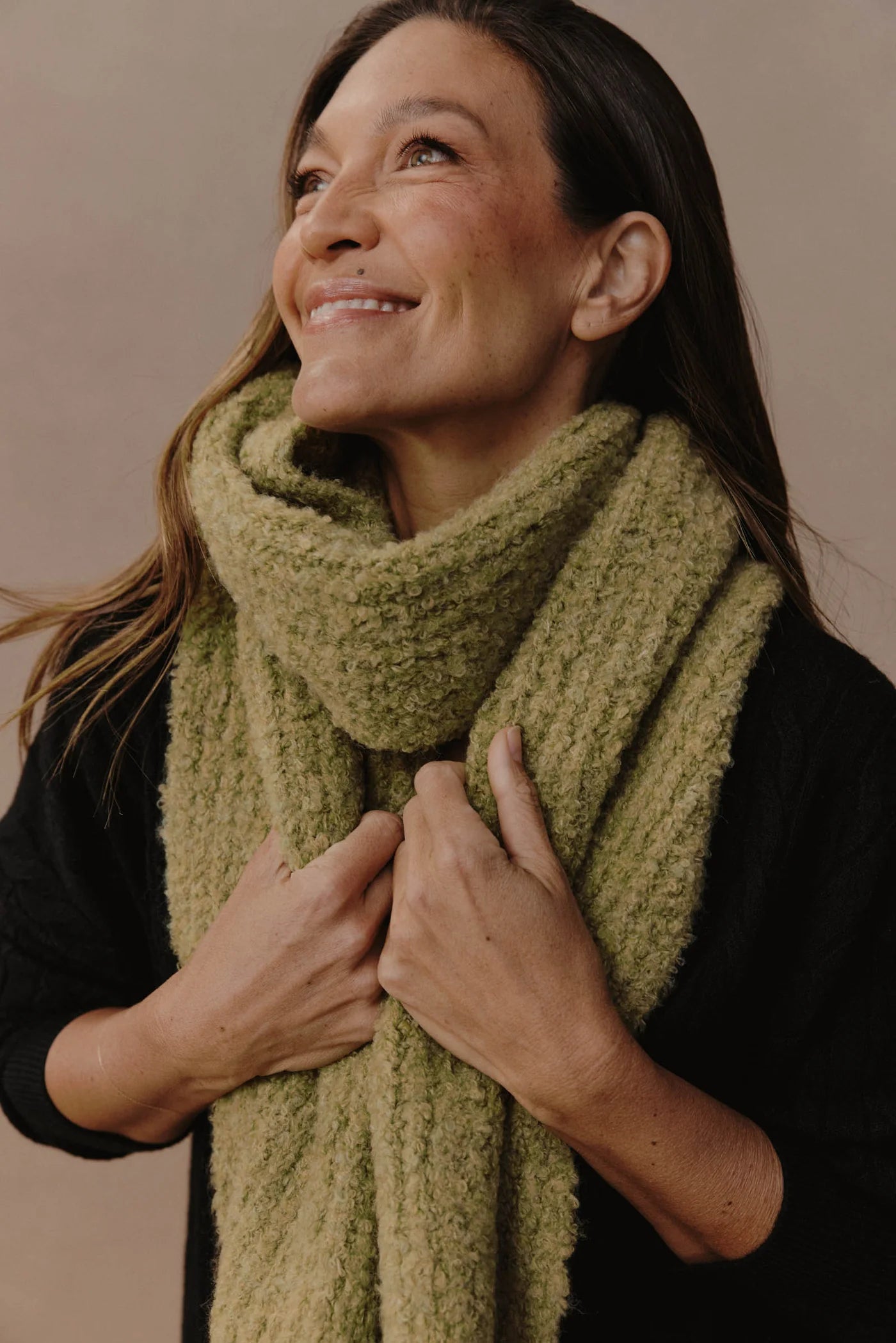 Image of Woman wearing a Eb & Ive green scarf against a beige background