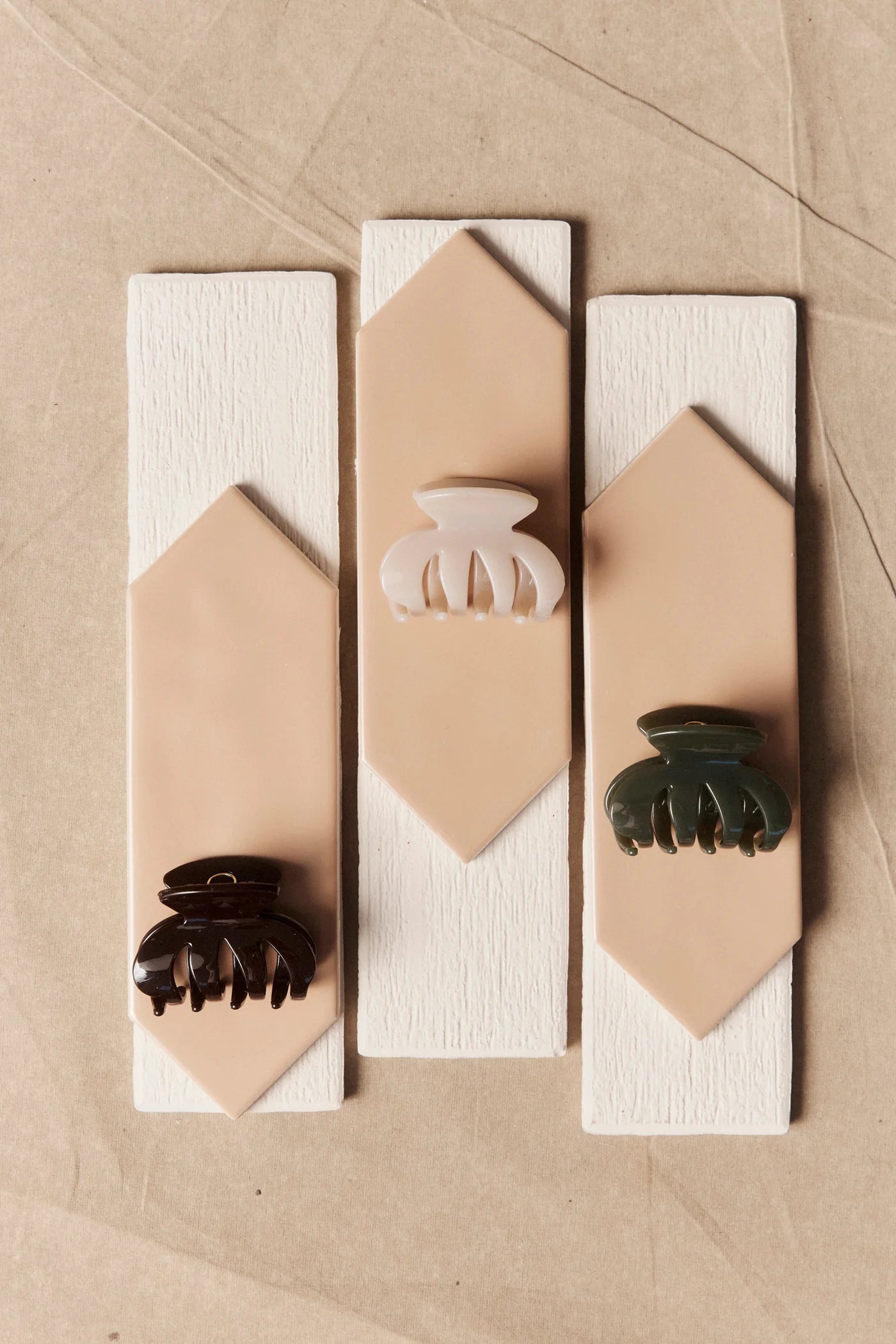 Image of Three Eb & Ive hair clips on geometric wooden blocks against a beige background