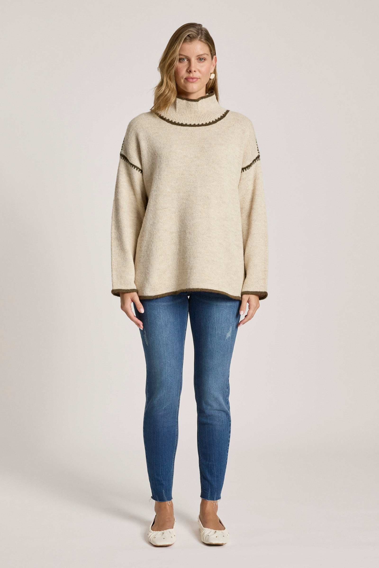 Image of Woman wearing a Eb & Ive beige sweater and blue jeans on a white background
