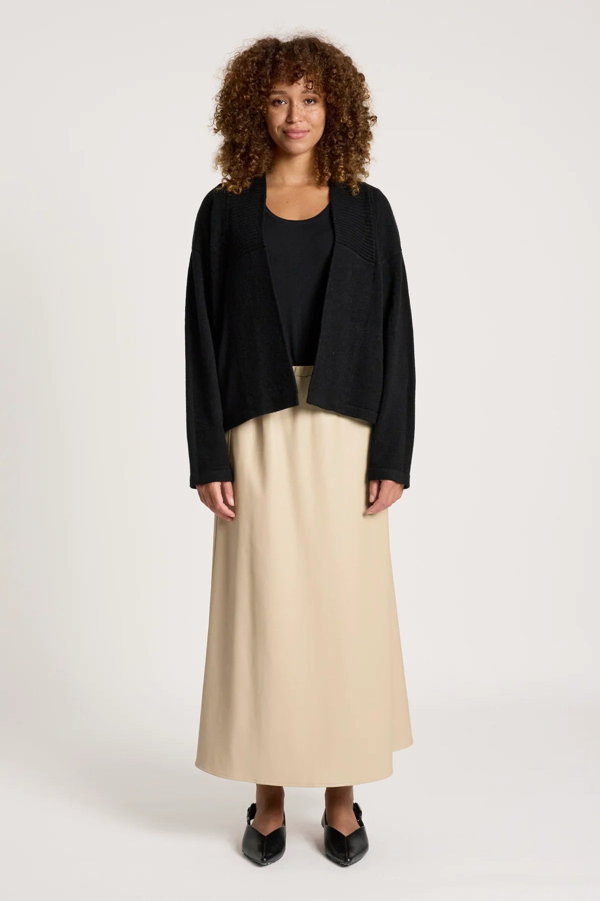 Image of Woman wearing a Eb & Ive black cardigan and beige skirt on a white background