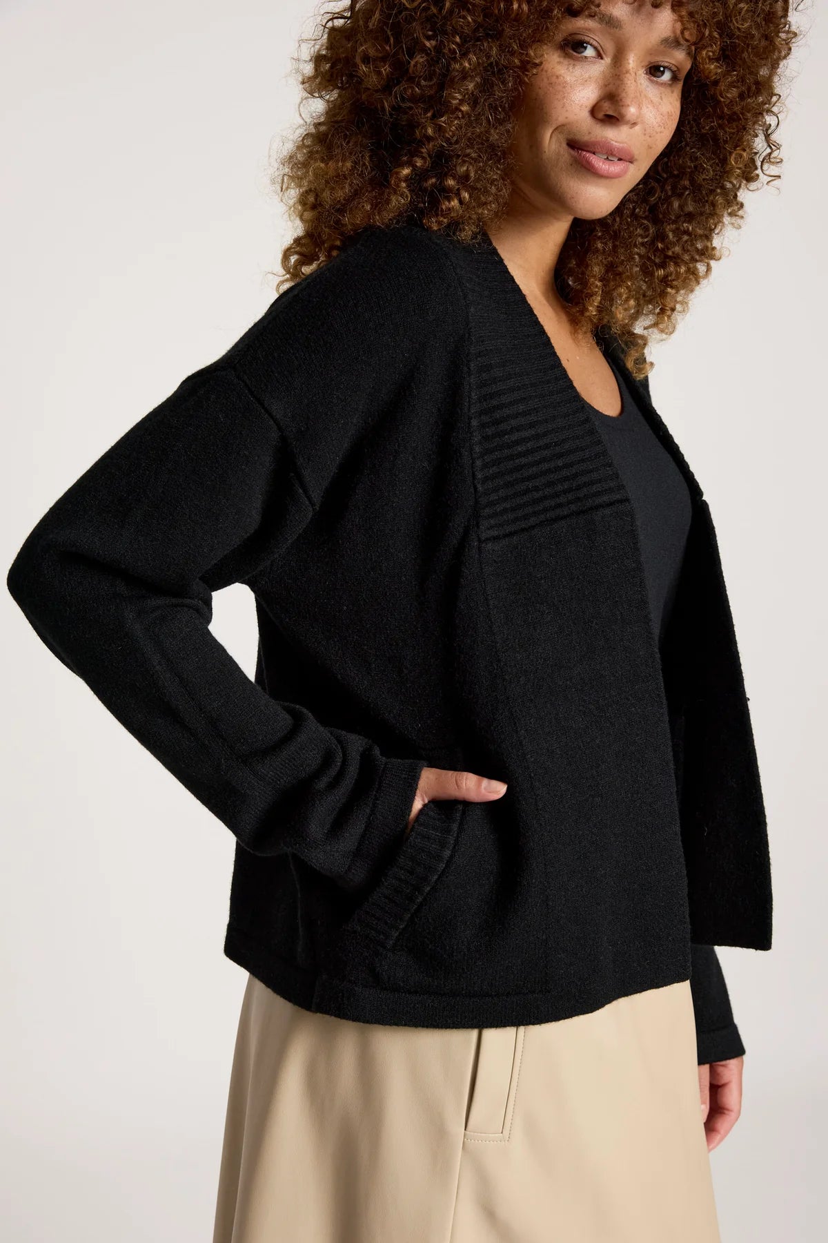 Image of Woman wearing a Eb & Ive black cardigan over a black top with beige pants on a white background