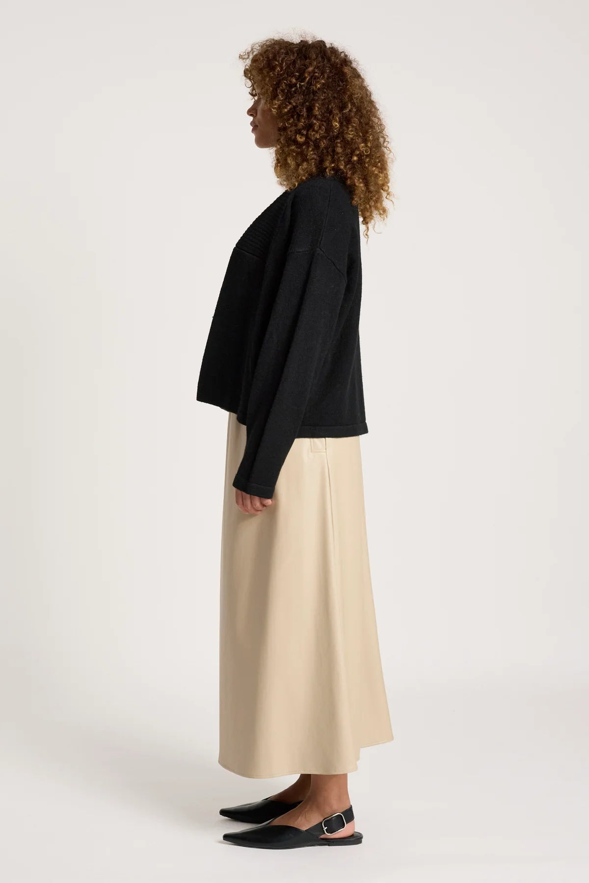 Image of Woman wearing a Eb & Ive black cardi and beige pants on a white background