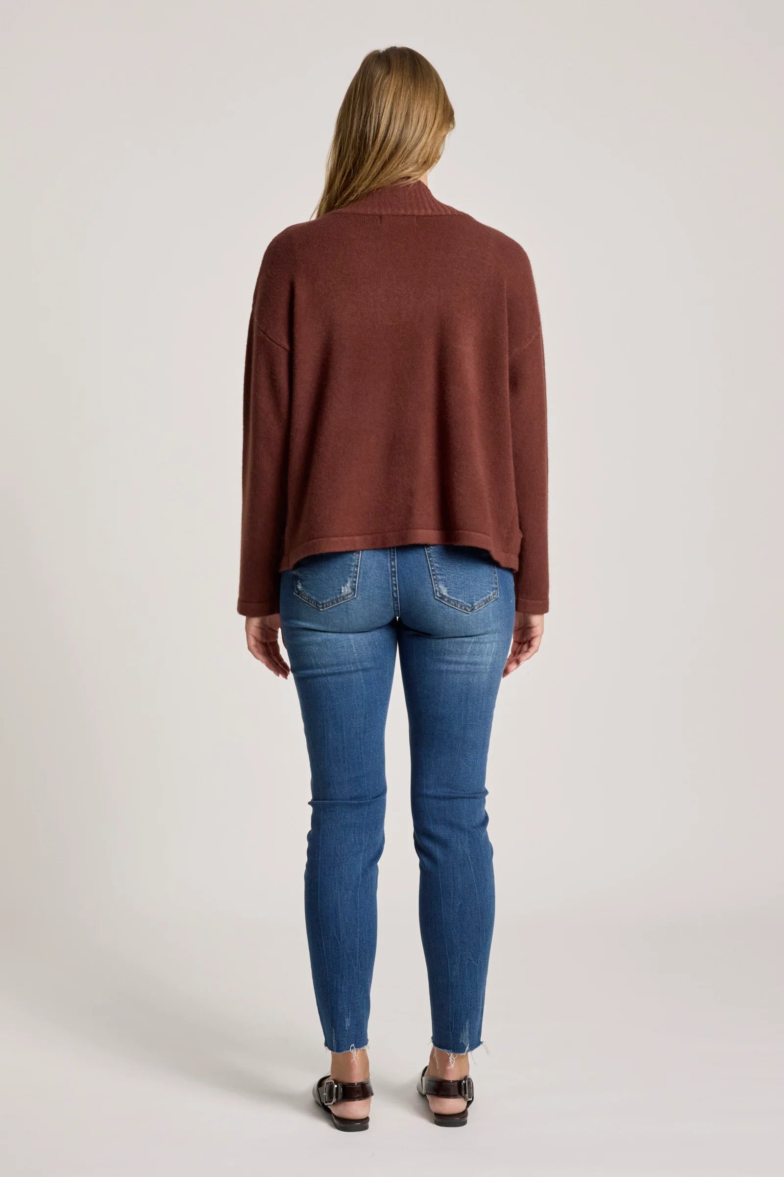 Image of Woman wearing a Eb & Ive brown sweater and blue jeans on a plain background