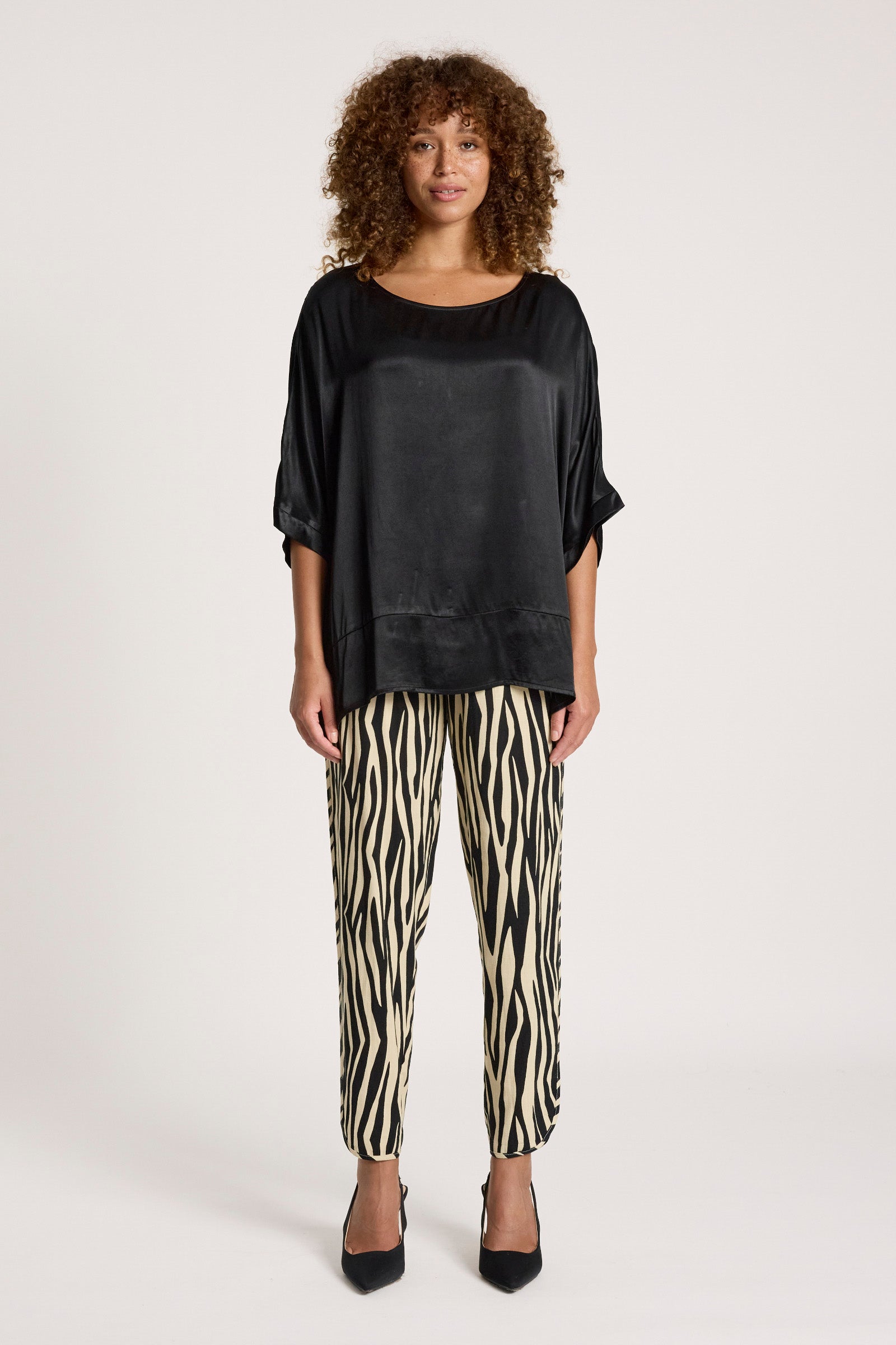 Image of Woman wearing a Eb & Ive black top and zebra print pants on a white background