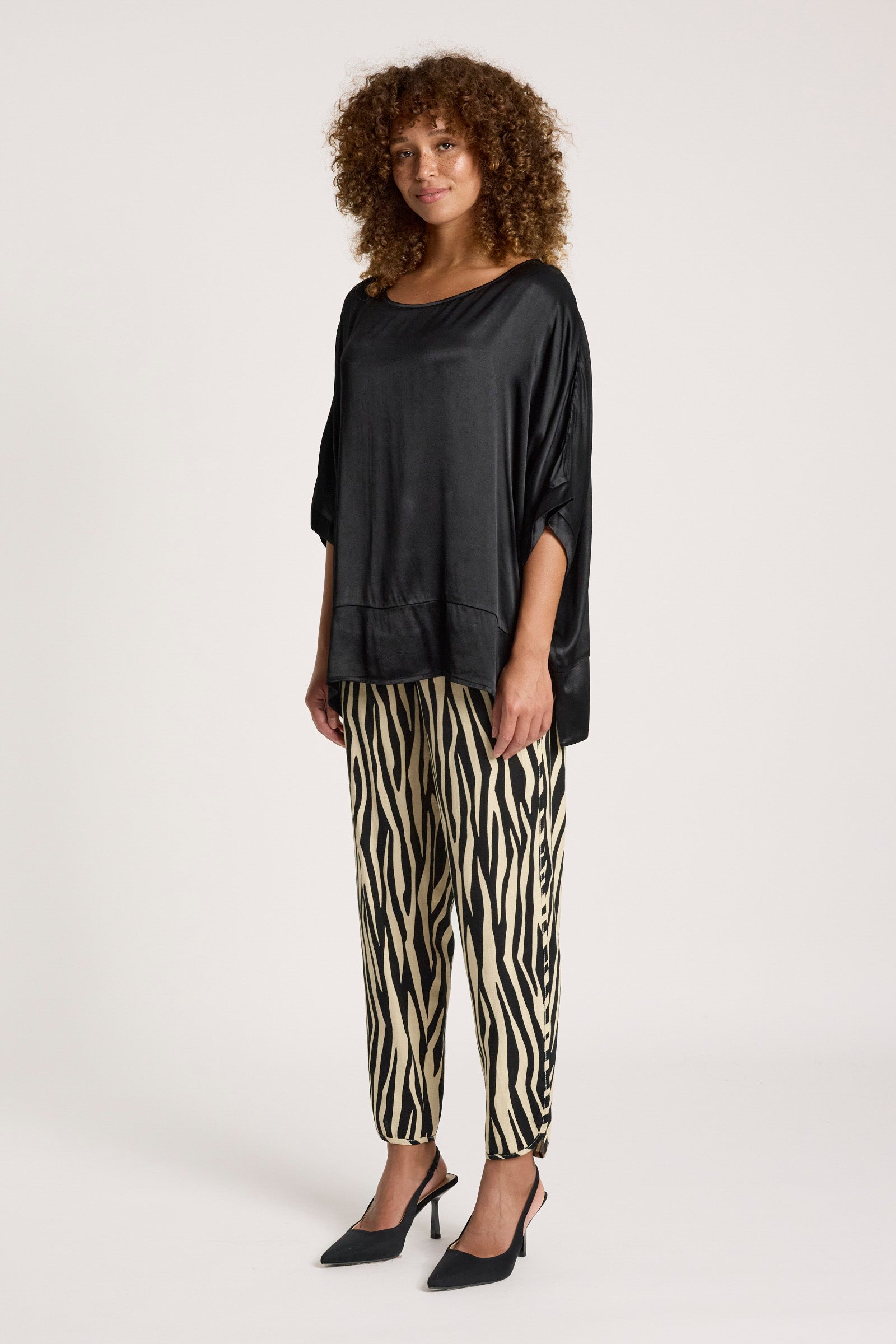 Image of Woman wearing a Eb & Ive black oversized top and zebra print pants on a white background