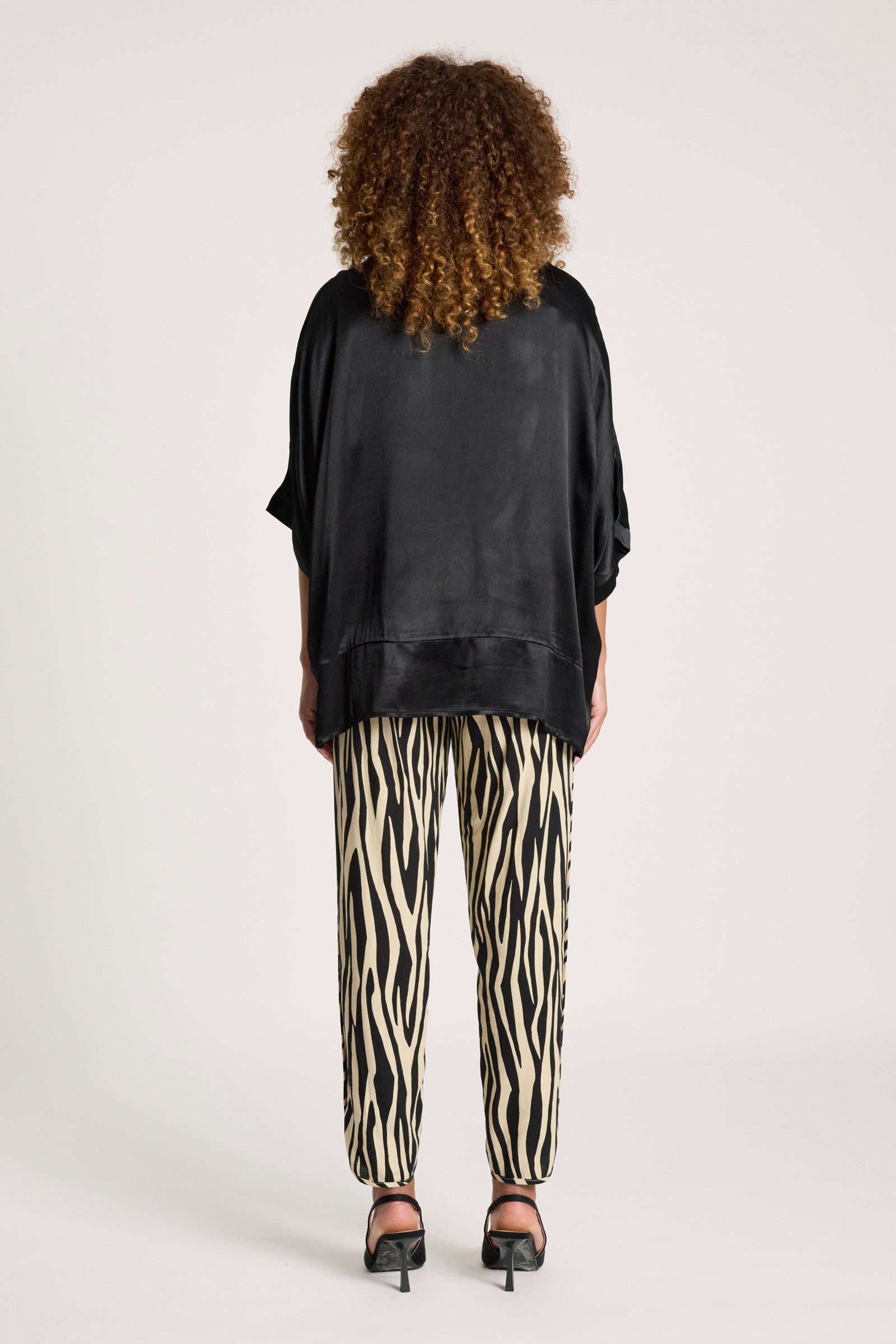 Image of Person wearing a Eb and Ive black top and zebra-striped pants on a white background