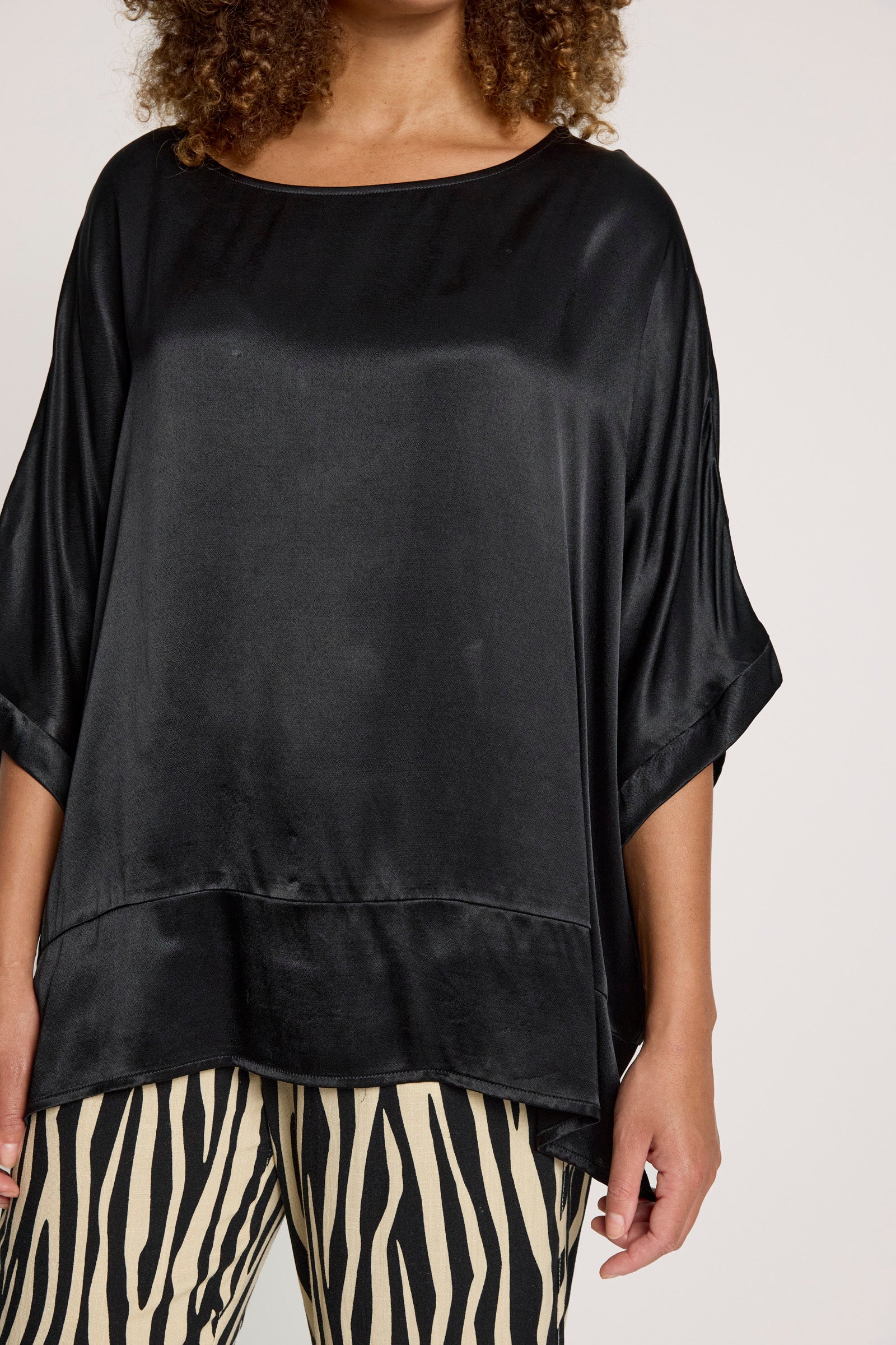 Image of Person wearing a Eb & Ive black satin top and zebra print pants on a white background