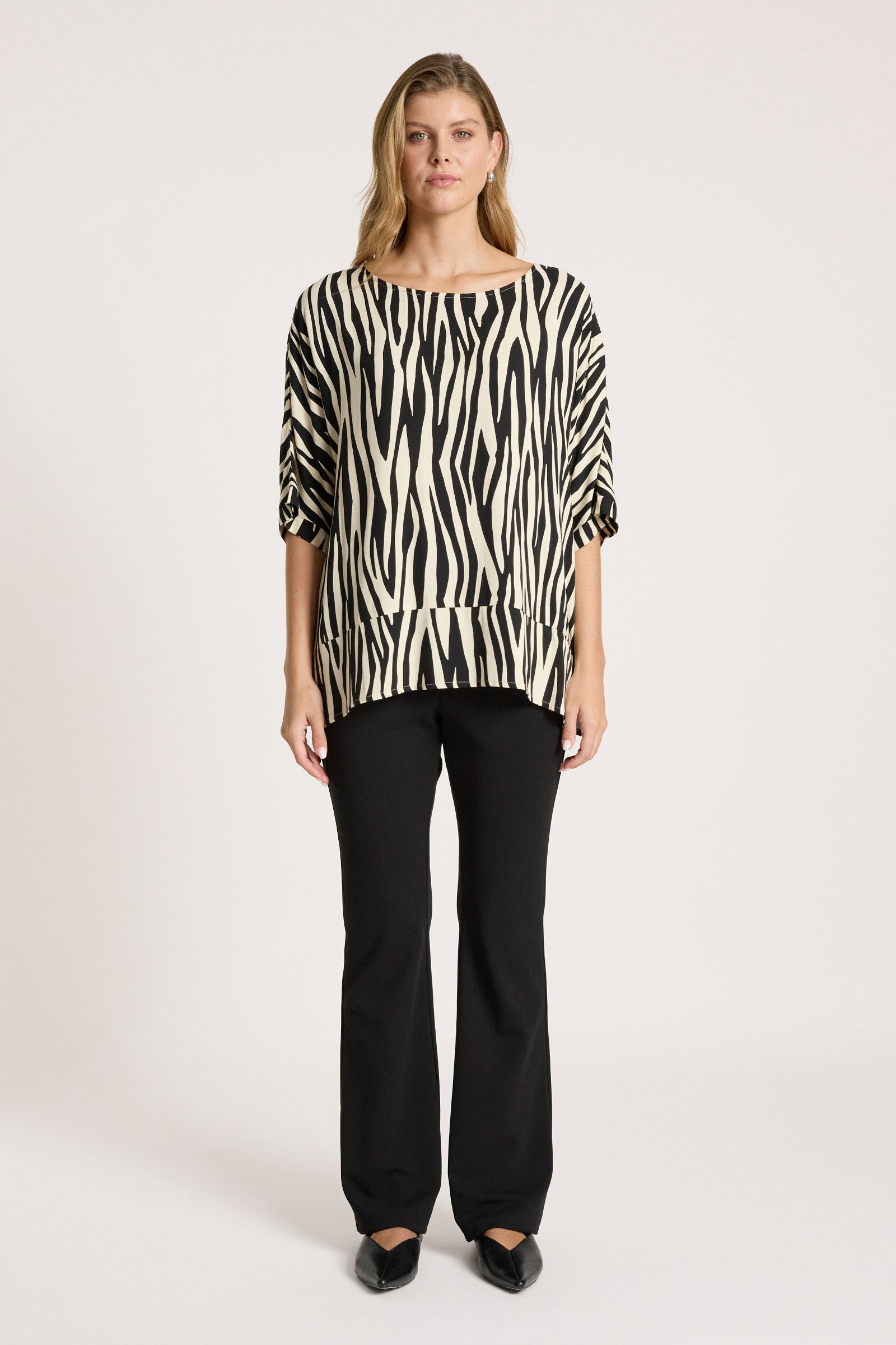 Woman wearing a Eb & Ive zebra print top and black pants on a white background