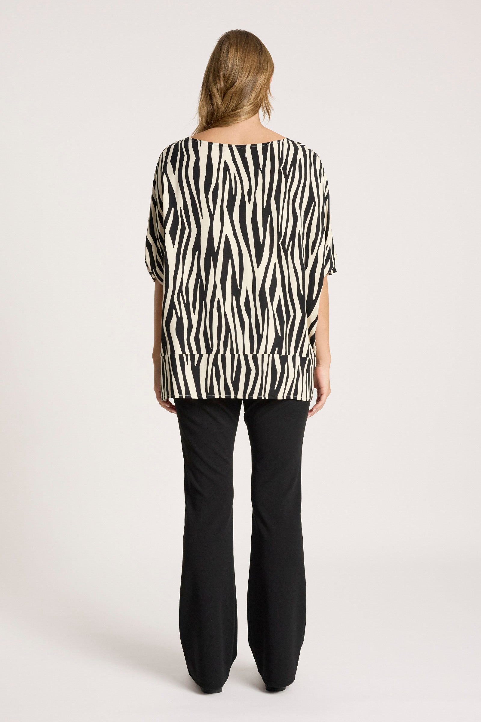 Woman wearing a Eb & Ive zebra print top and black pants on a white background