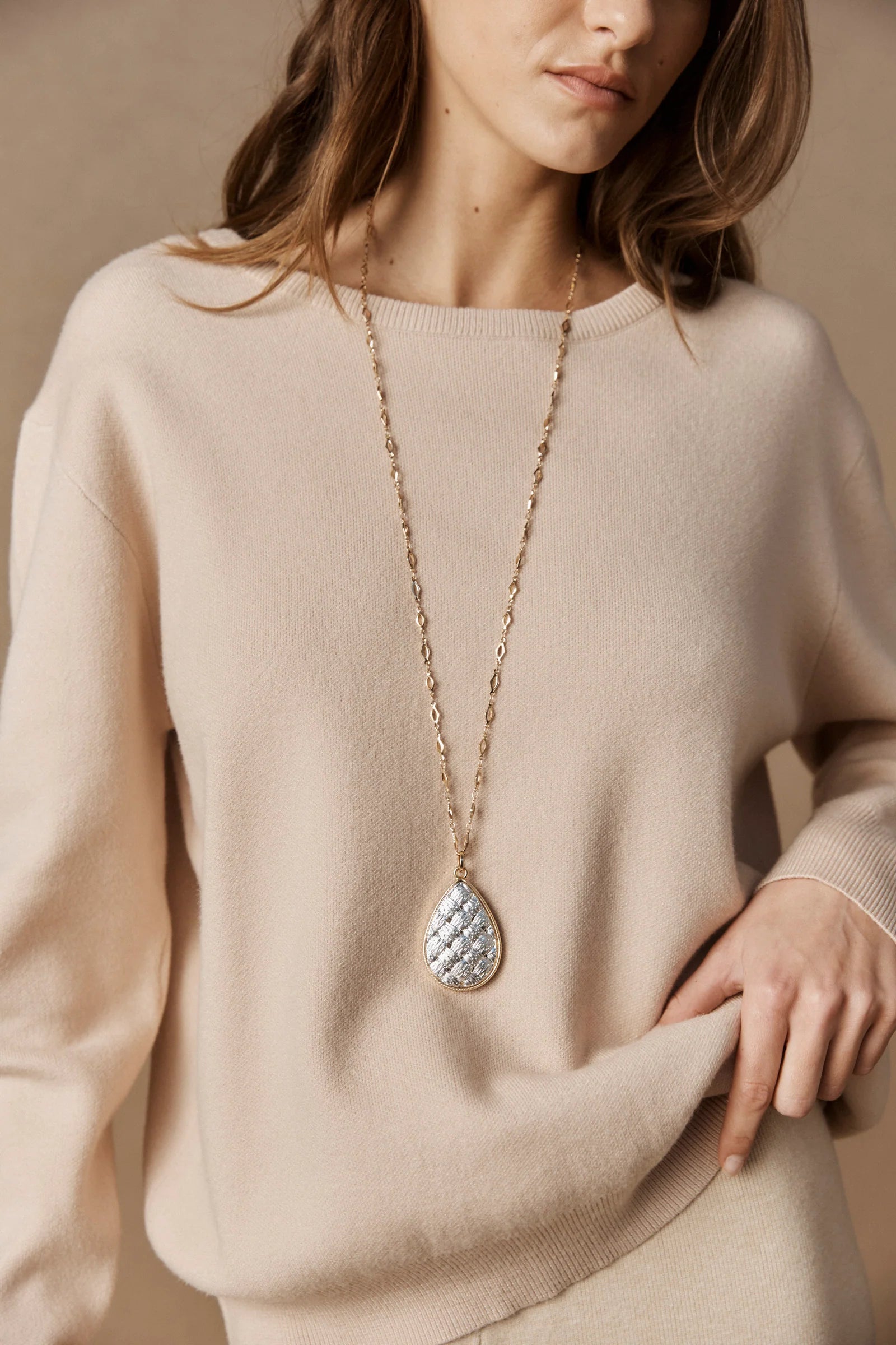 Image of Woman wearing a beige sweater with a Eb & Ive long necklace featuring a teardrop-shaped pendant.