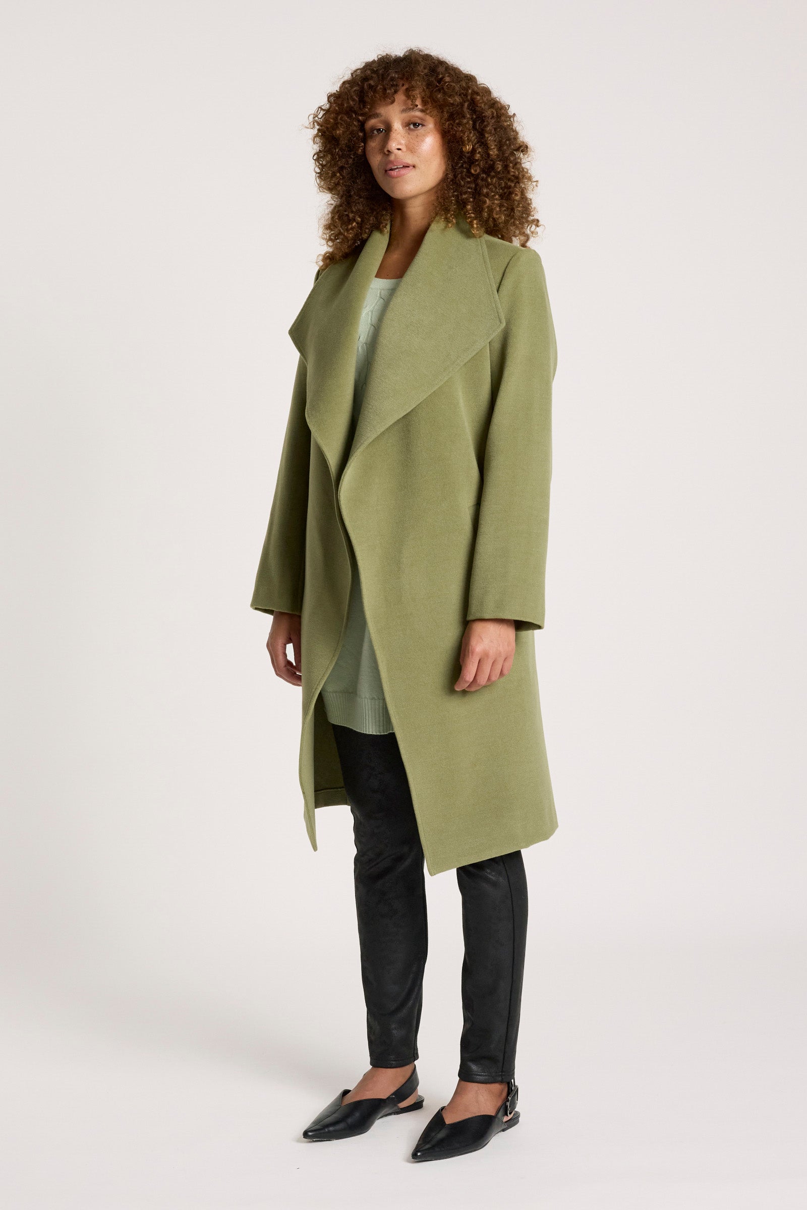 Image of Woman wearing a Eb & Ive green coat on a white background