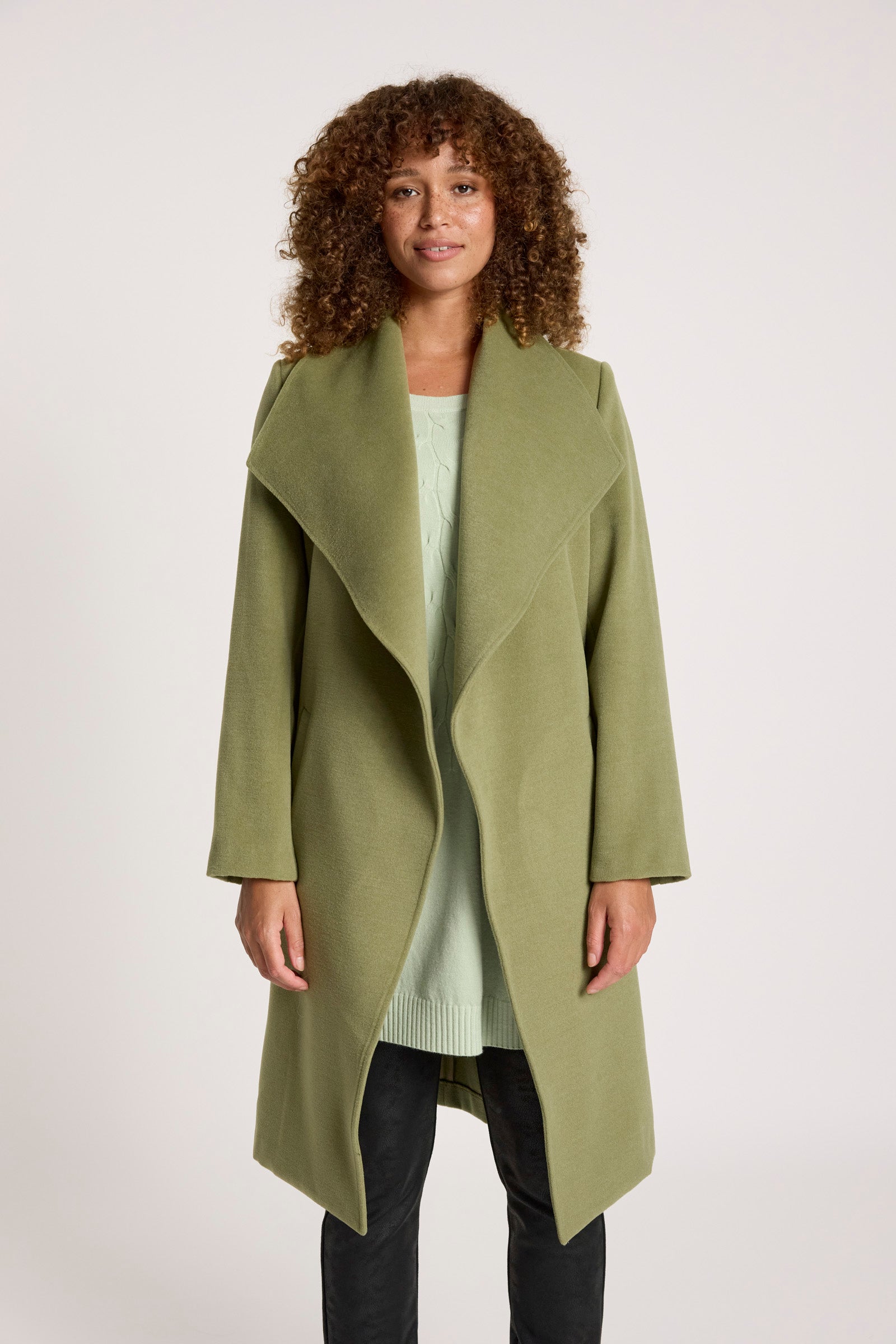Woman wearing a Eb & Ive green coat on a white background