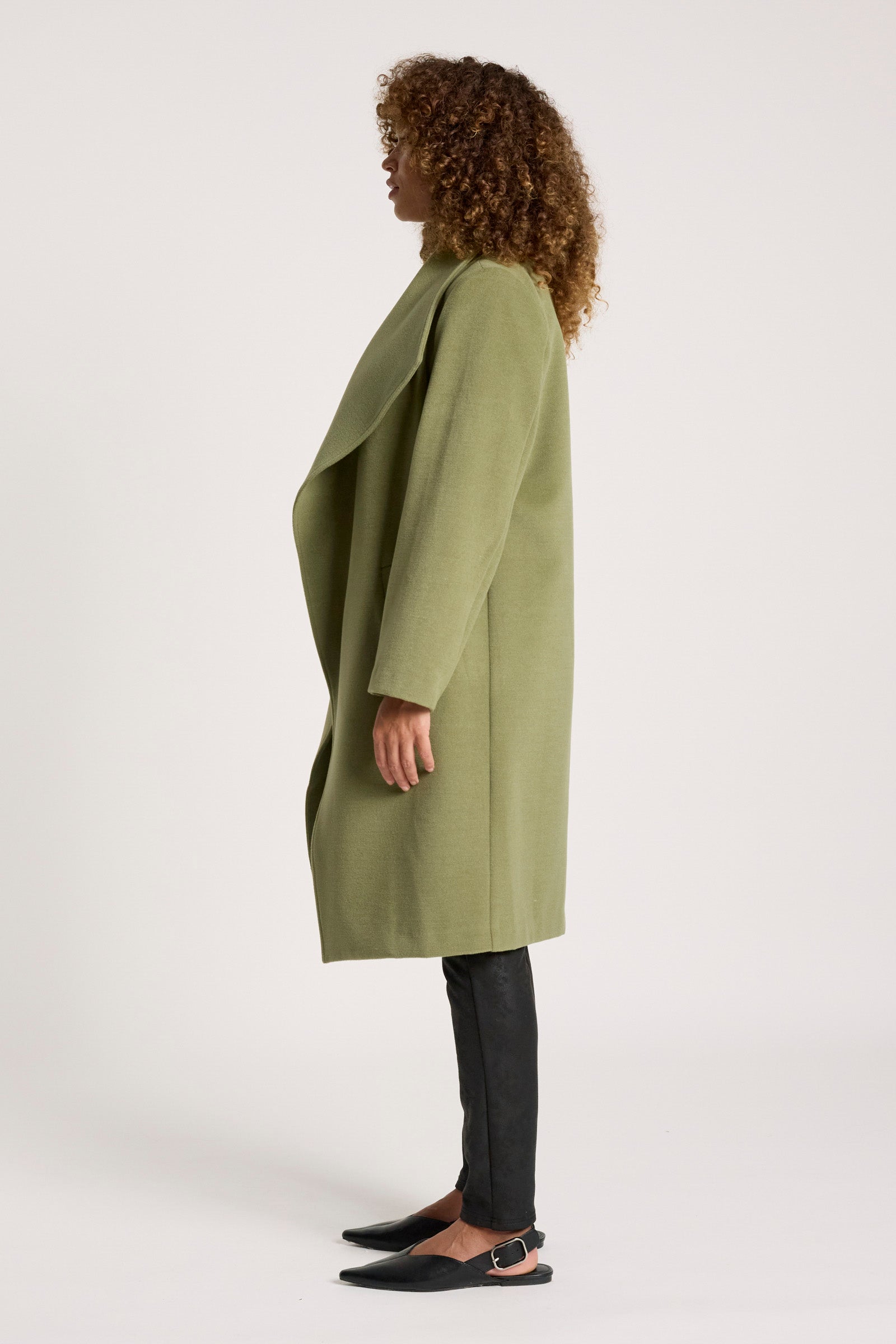 Image of Woman wearing a Eb & Ive green coat on a white background