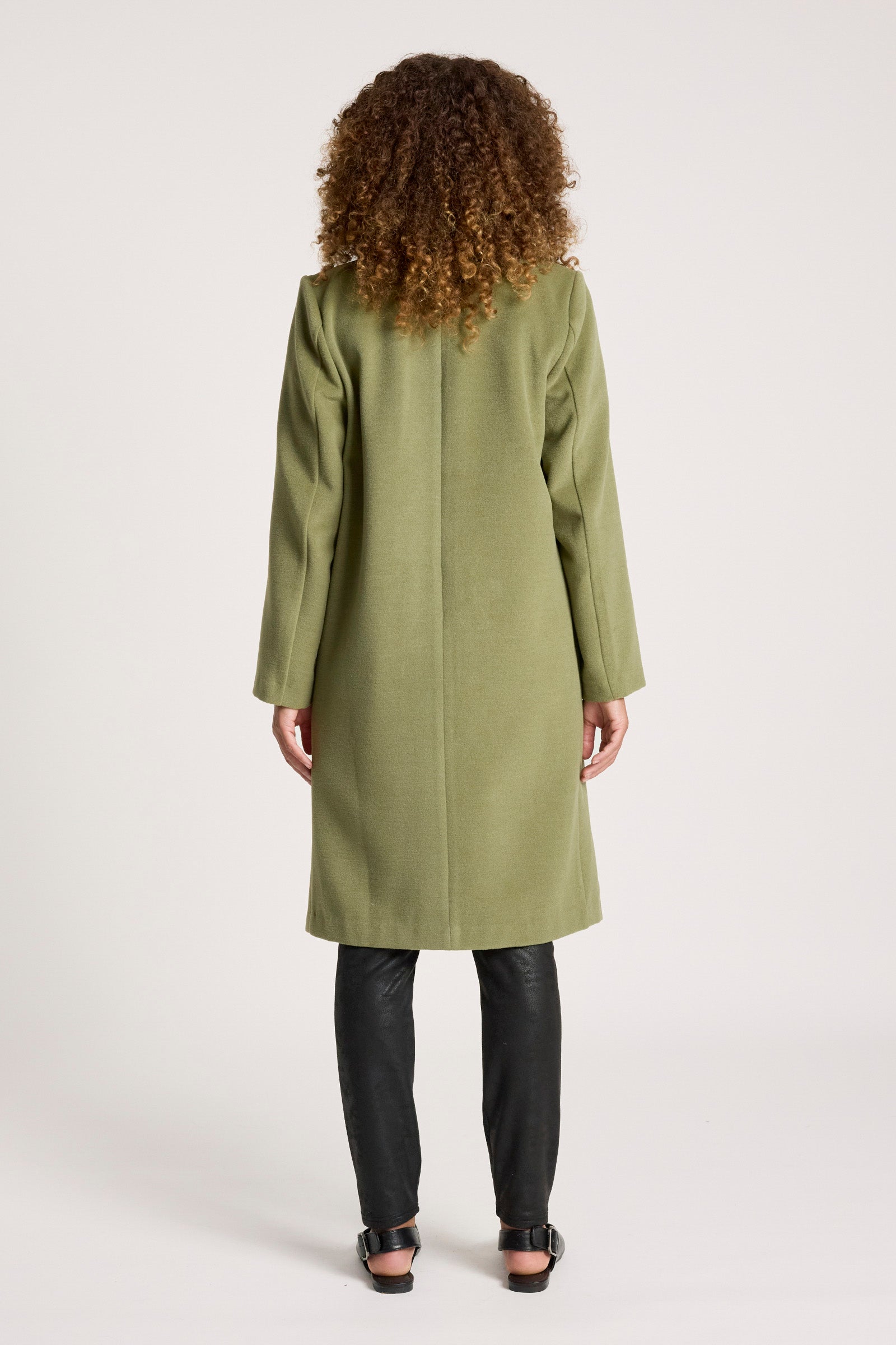 Woman wearing a Eb & Ive green coat on a white background
