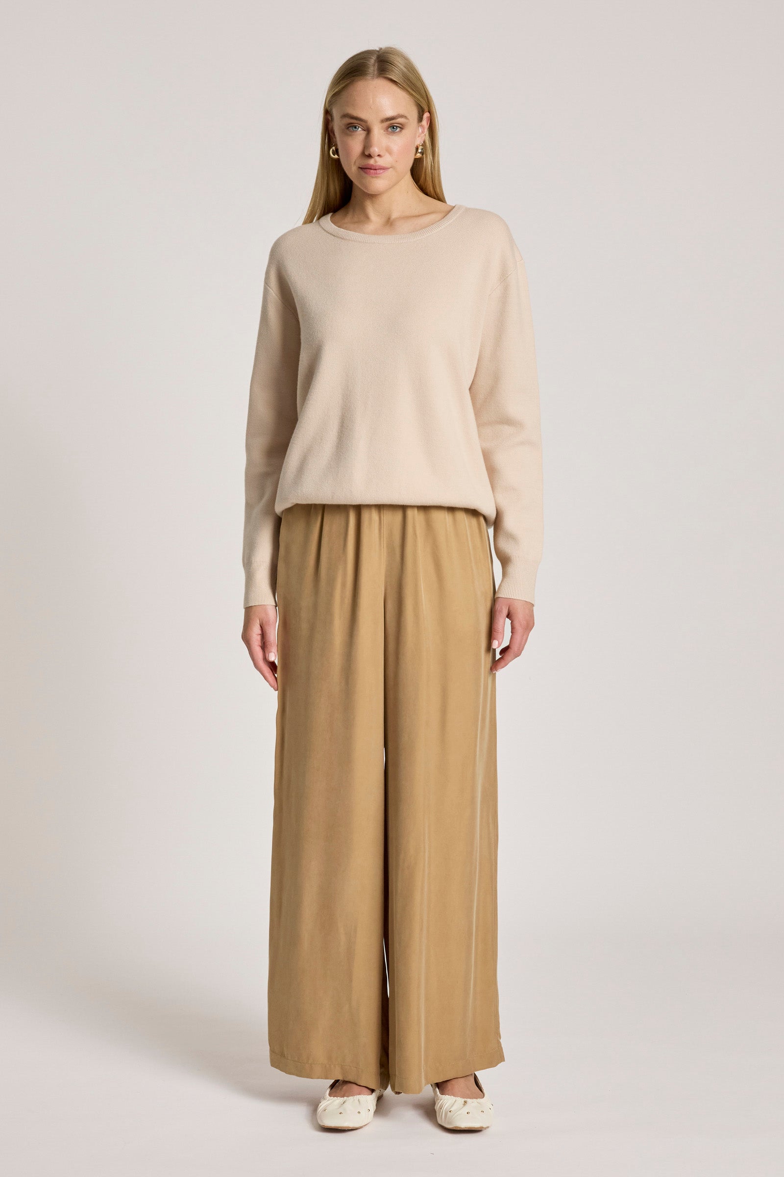 Image of Woman wearing a Eb and Ive beige sweater and wide-leg pants on a light gray background