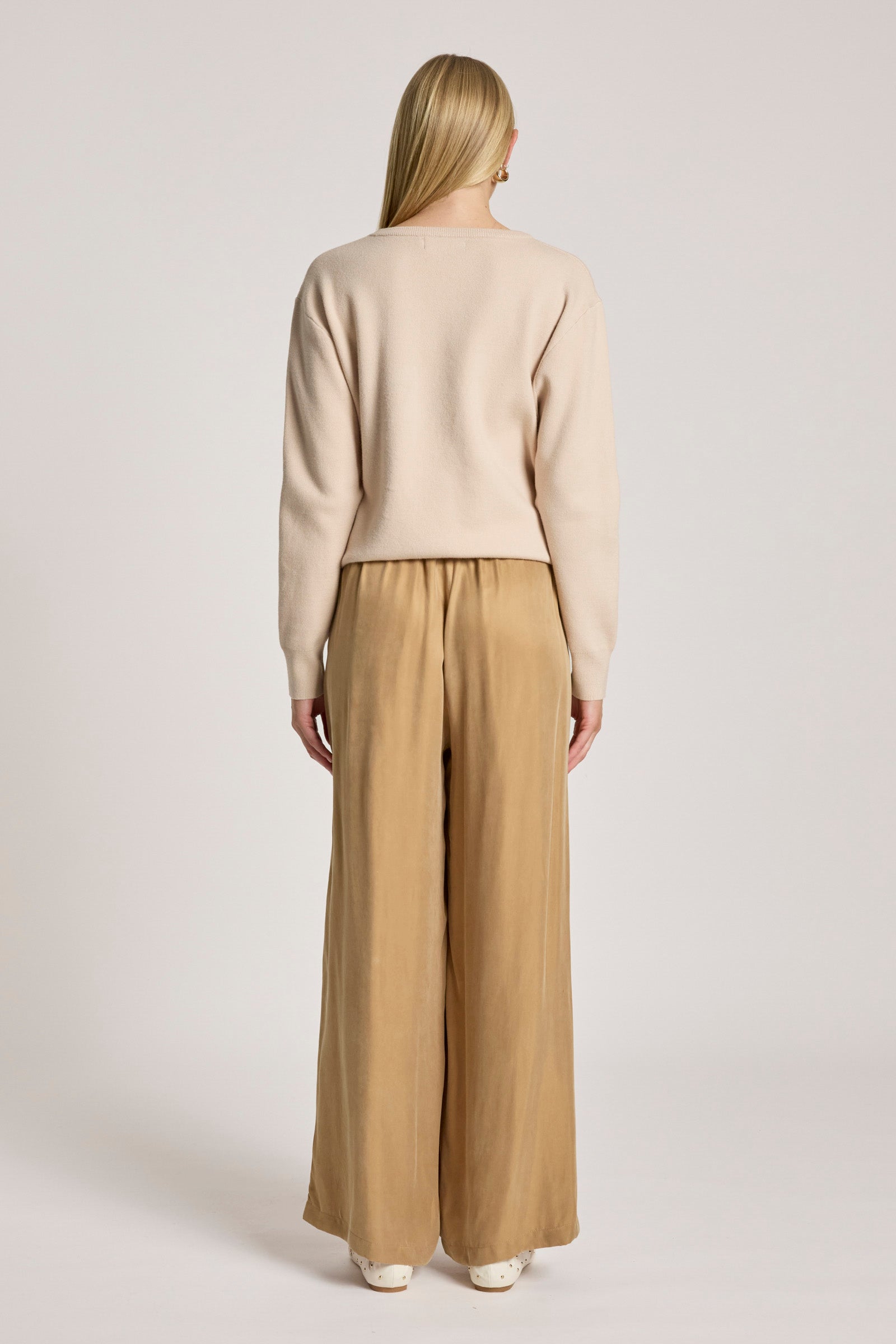 Woman wearing a Eb & Ive beige sweater and tan pants on a white background