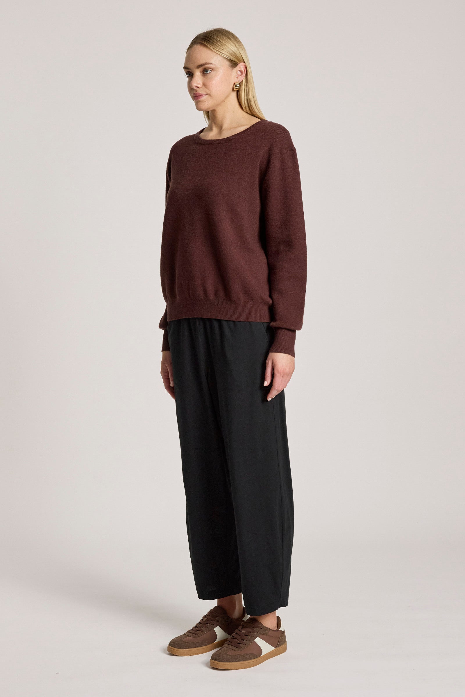 Image of Woman wearing a Eb & Ive brown sweater and black pants on a white background