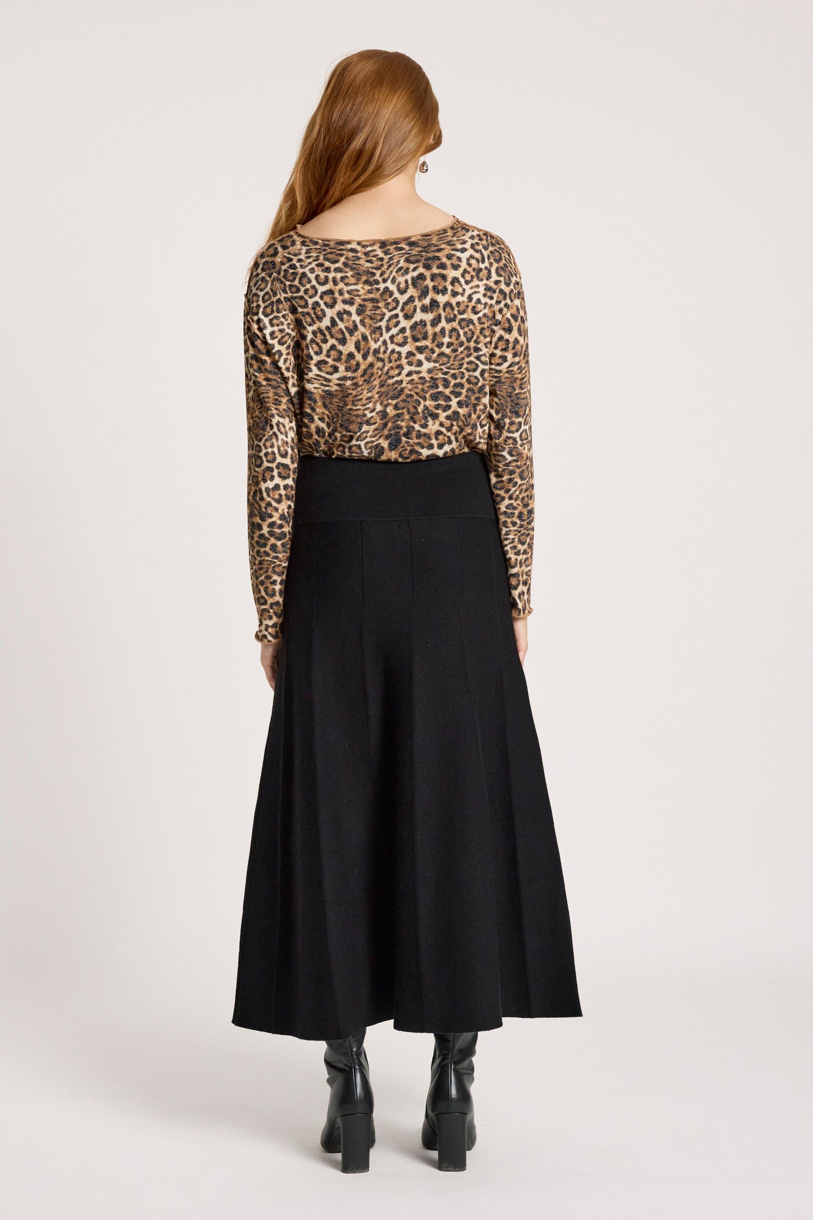 Woman wearing a leopard print top and Eb & Ive black skirt on a white background