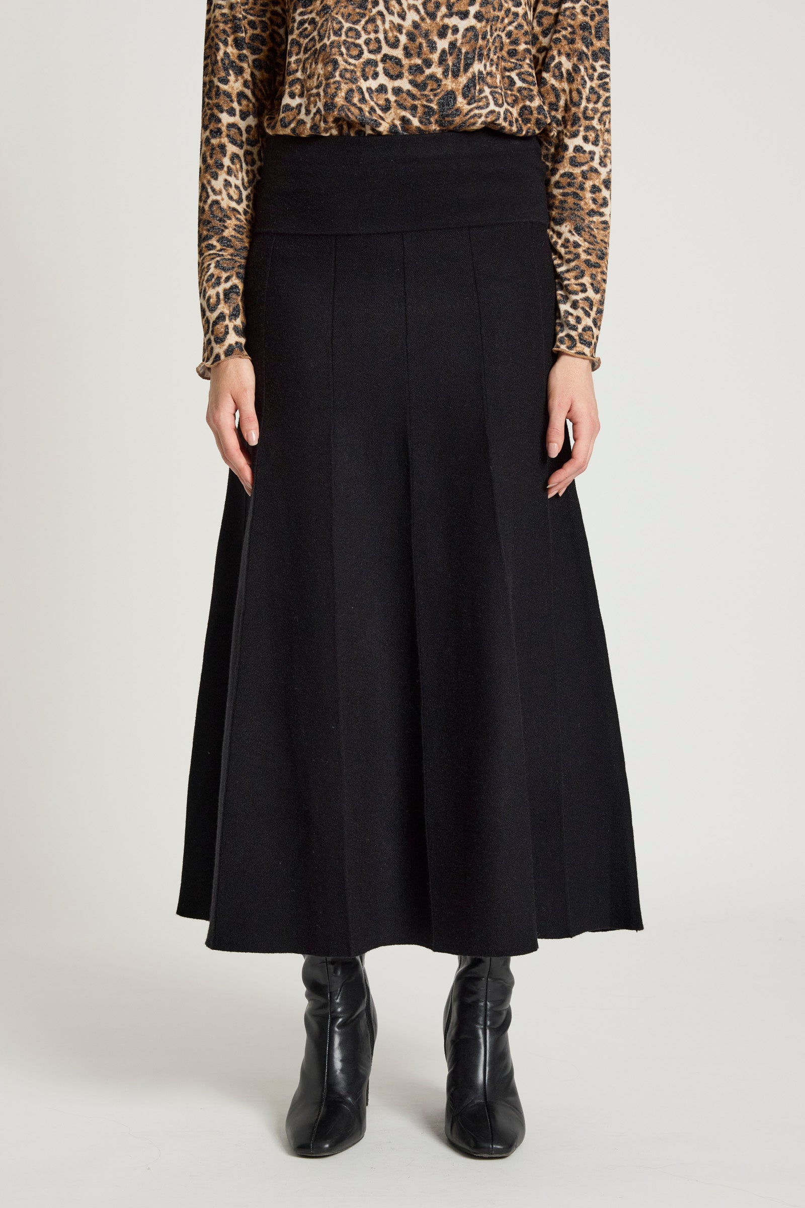 Woman wearing a Eb & Ive black skirt with a leopard print top on a white background
