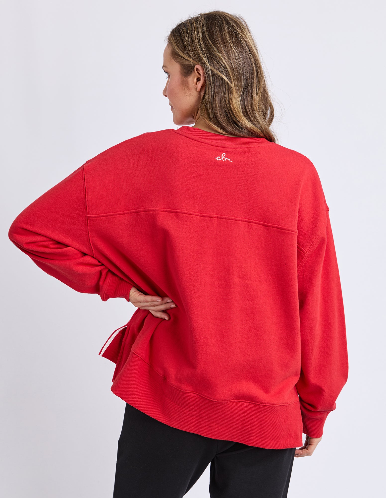 Person wearing a red jumper with an elm logo on the back against a white background