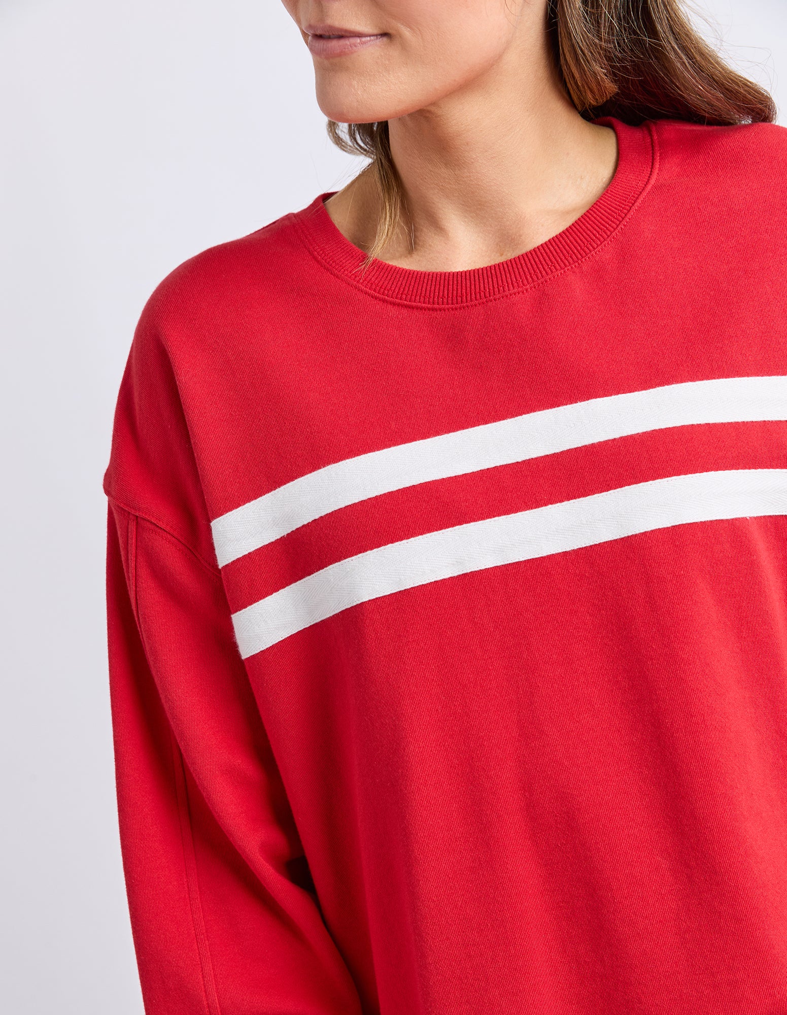 Image of Red jumper with white stripes worn by a person on a light grey background