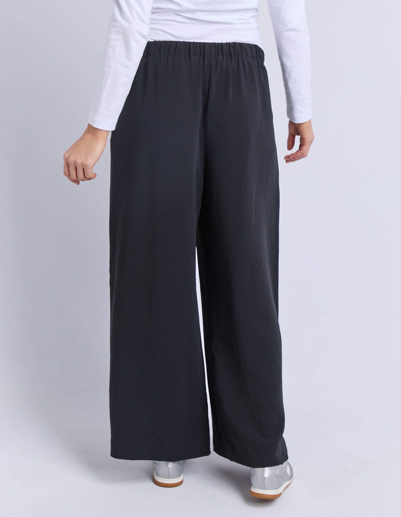 Image of Back view of a woman wearing Elm black wide-leg pants on a white background
