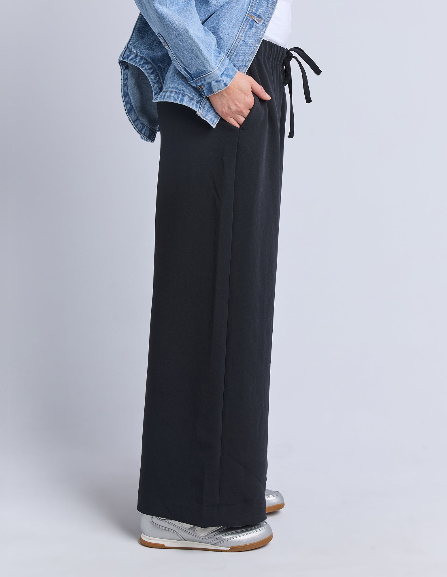 Image of Sideview of a woman wearing black wide-leg pants with a light grey background