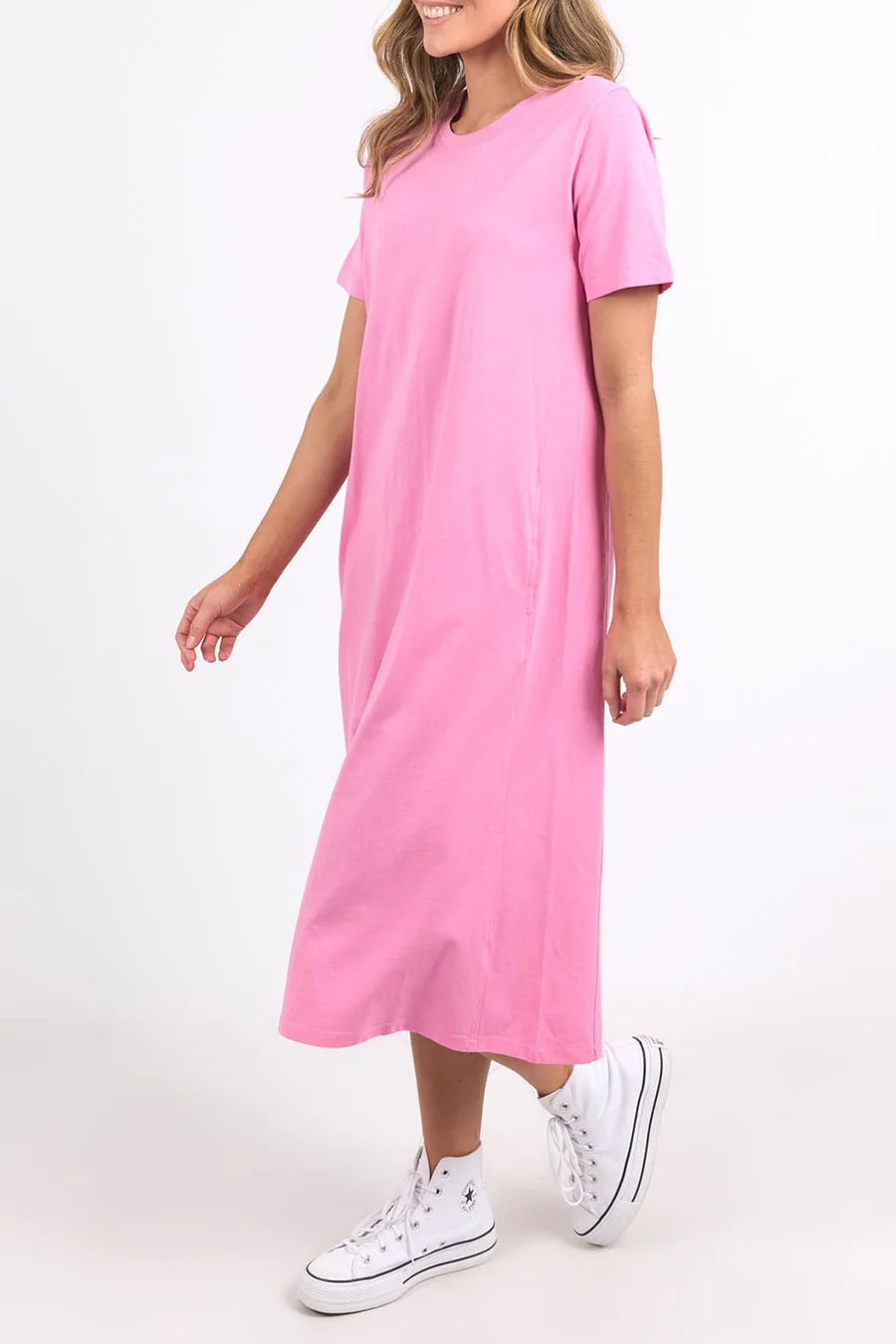 Image of Woman wearing a Elm pink dress with white sneakers on a white background