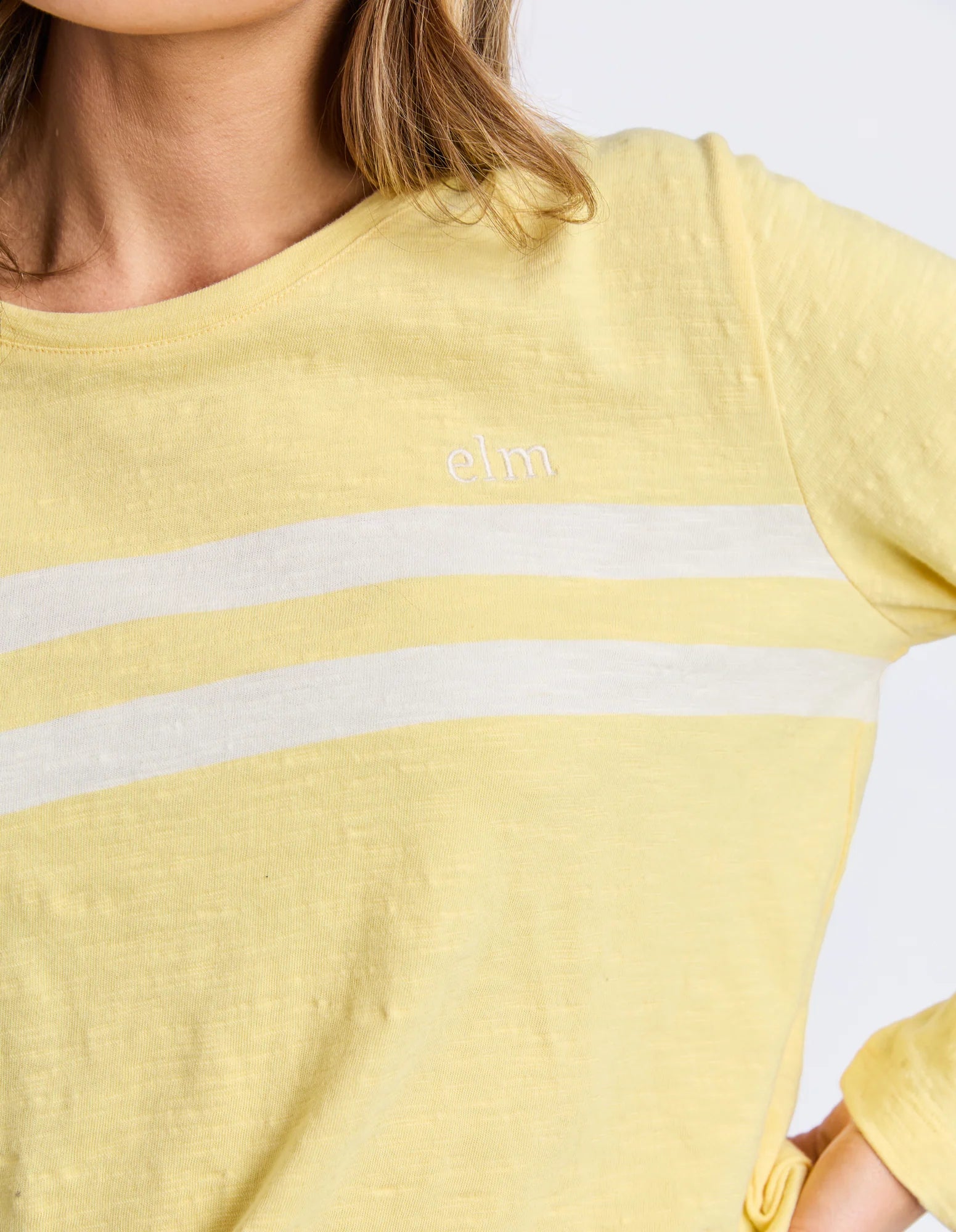 Elm Yellow t-shirt with white stripes and a brand logo on a plain background