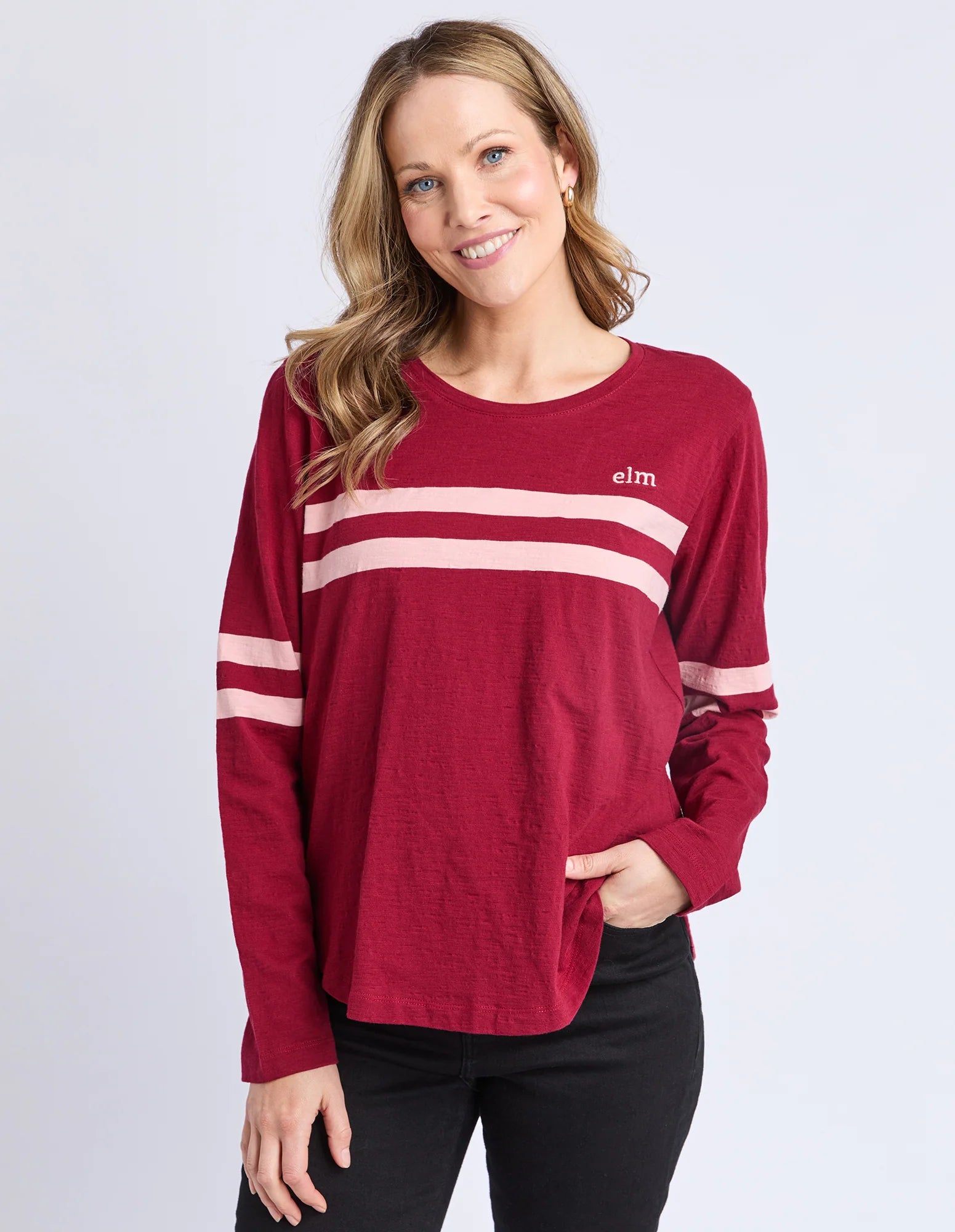 Image of Woman wearing a Elm red long-sleeve shirt with white stripes on a light gray background