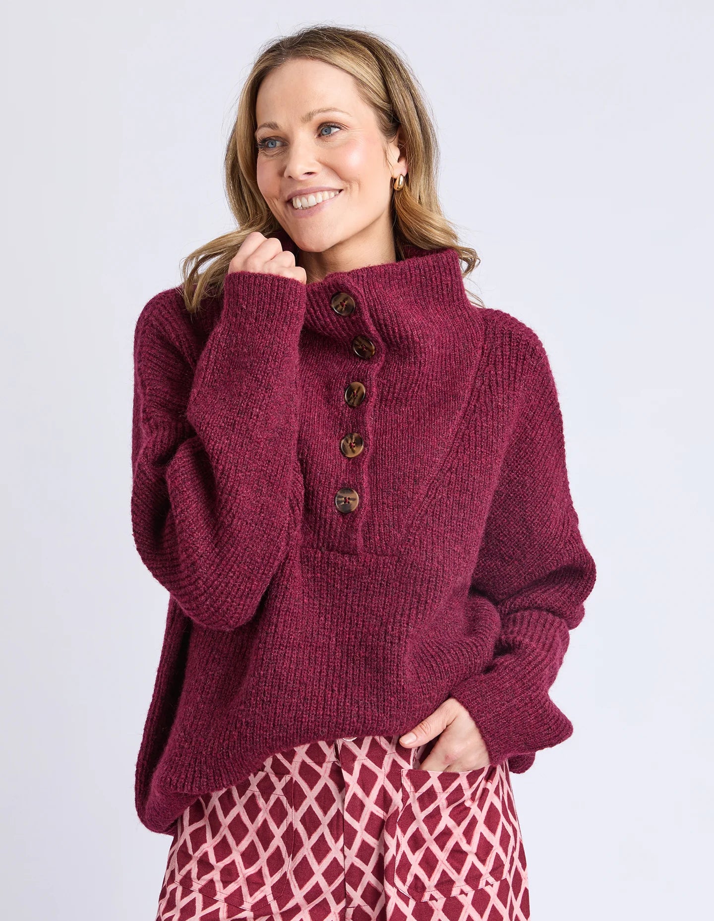 Image of Woman wearing a Elm maroon knitted sweater with buttons on a light gray background