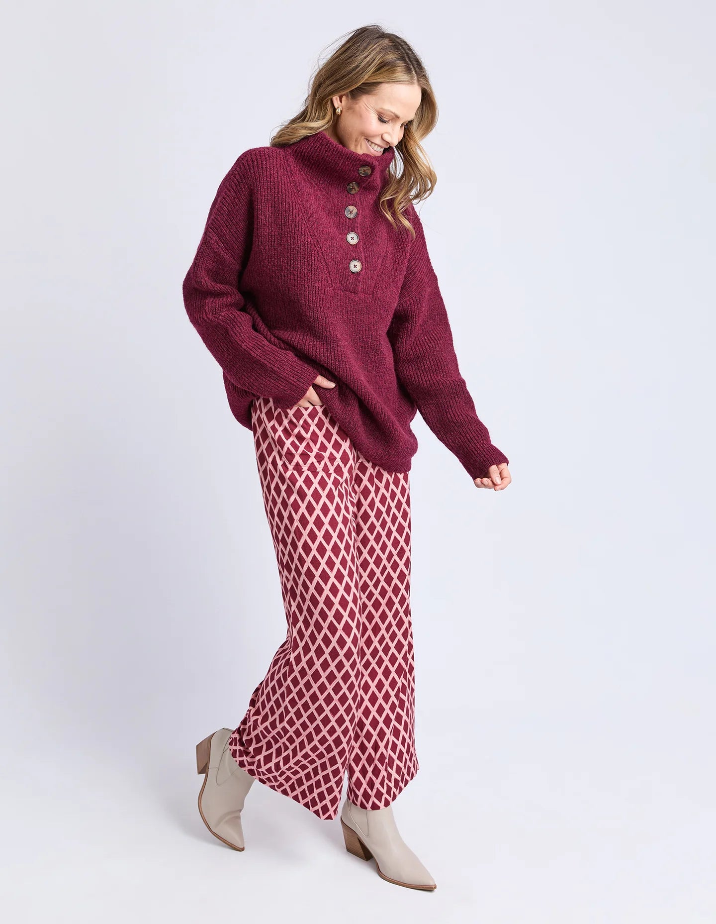 Image of Woman wearing a Elm burgundy sweater and patterned skirt on a white background